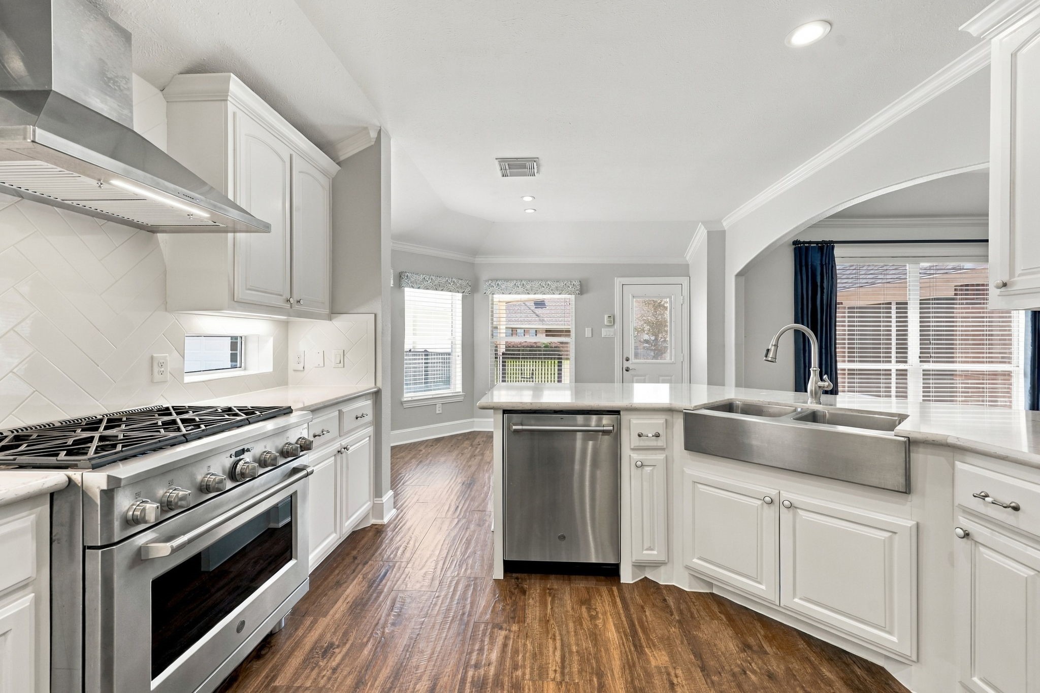 The farmhouse stainless steel sink, paired with a sleek gooseneck chrome faucet, adds charm and character to the Kitchen and is perfectly situated within the large Breakfast Bar, creating a functional and inviting space for meal preparation and casual dining.