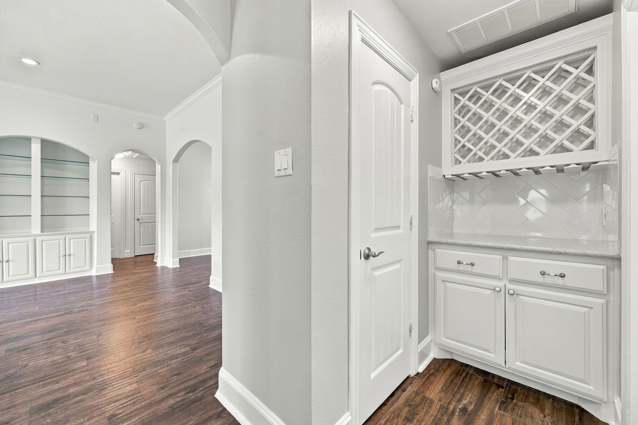The Butlers Pantry, or Dry Bar, is beautifully appointed with a wine rack to display your favorite selections, convenient hanging storage for wine glasses, soft-close cabinetry and drawers, and additional pantry storage to the left. This thoughtfully designed space is perfect for entertaining while keeping the kitchen organized and clutter-free.