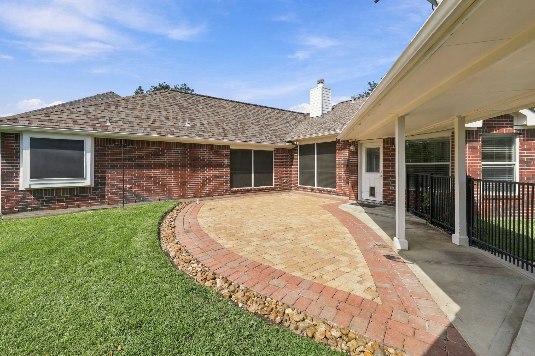The extended patio is beautifully finished with a decorative rock border, while the wrought-iron fence and gate along the breezeway help keep children and pets safely in the Backyard. The thoughtfully designed outdoor space offers both beauty and functionality for relaxing and entertaining.
