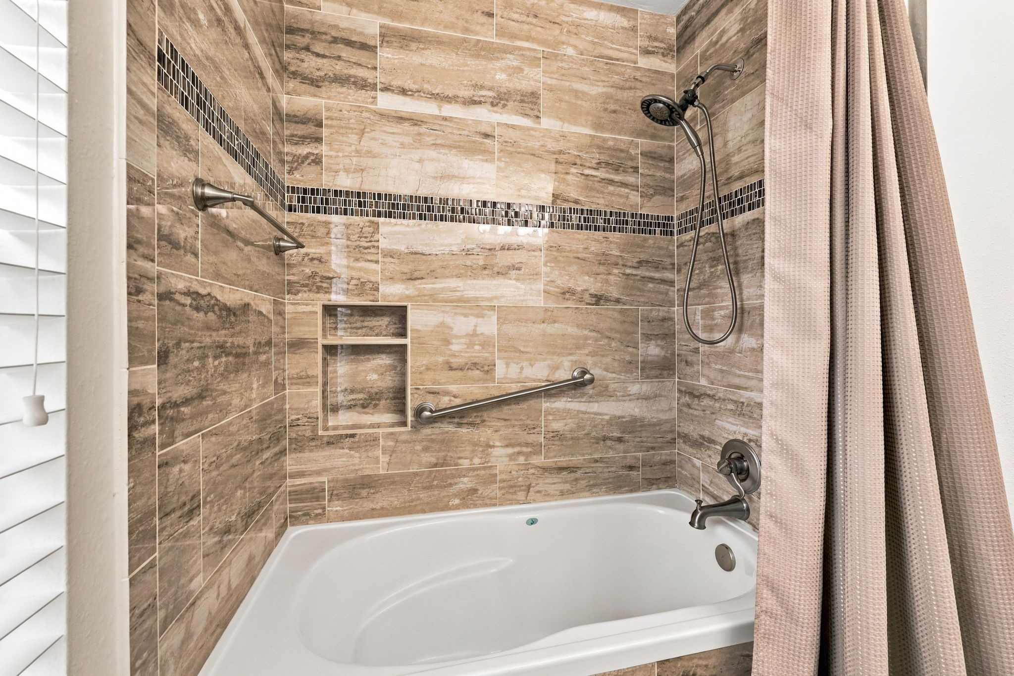 This Full Bath also features a tub/shower combination with designer 12x24 tiled walls accented by a decorative accent strip, complemented by brushed nickel fixtures, including a shower wand and faucet.