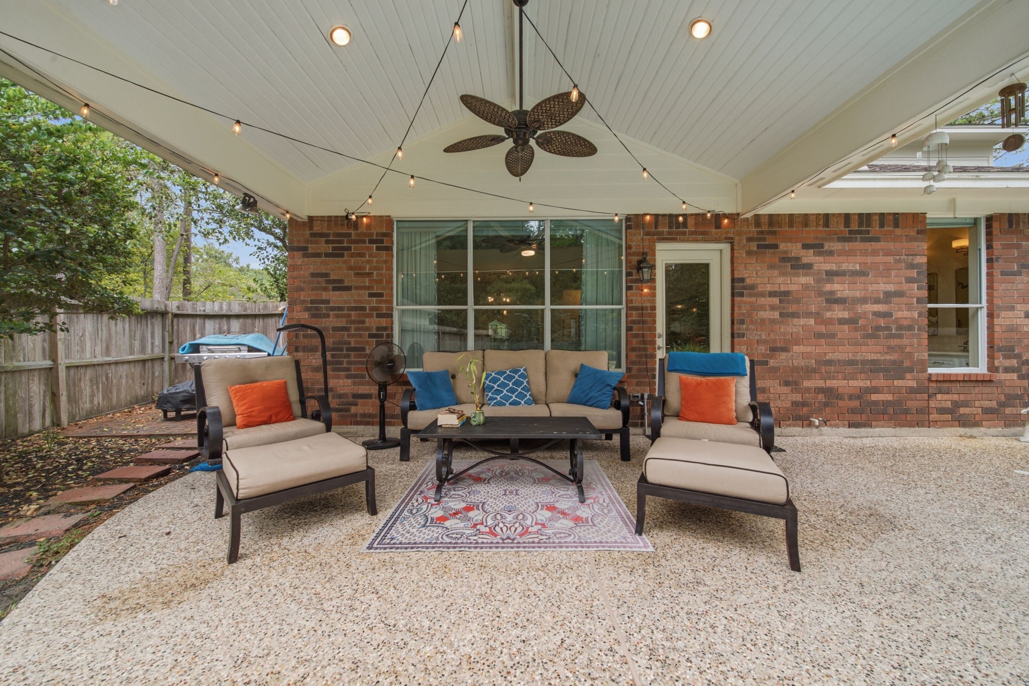 Extend your living space outdoors with this spacious covered porch featuring a vaulted ceiling, recessed lighting, and ceiling fan. With plenty of room for comfortable seating, it's an inviting setting for morning coffee, relaxed evenings or entertaining friends around the pool. Rain or shine, you're covered.