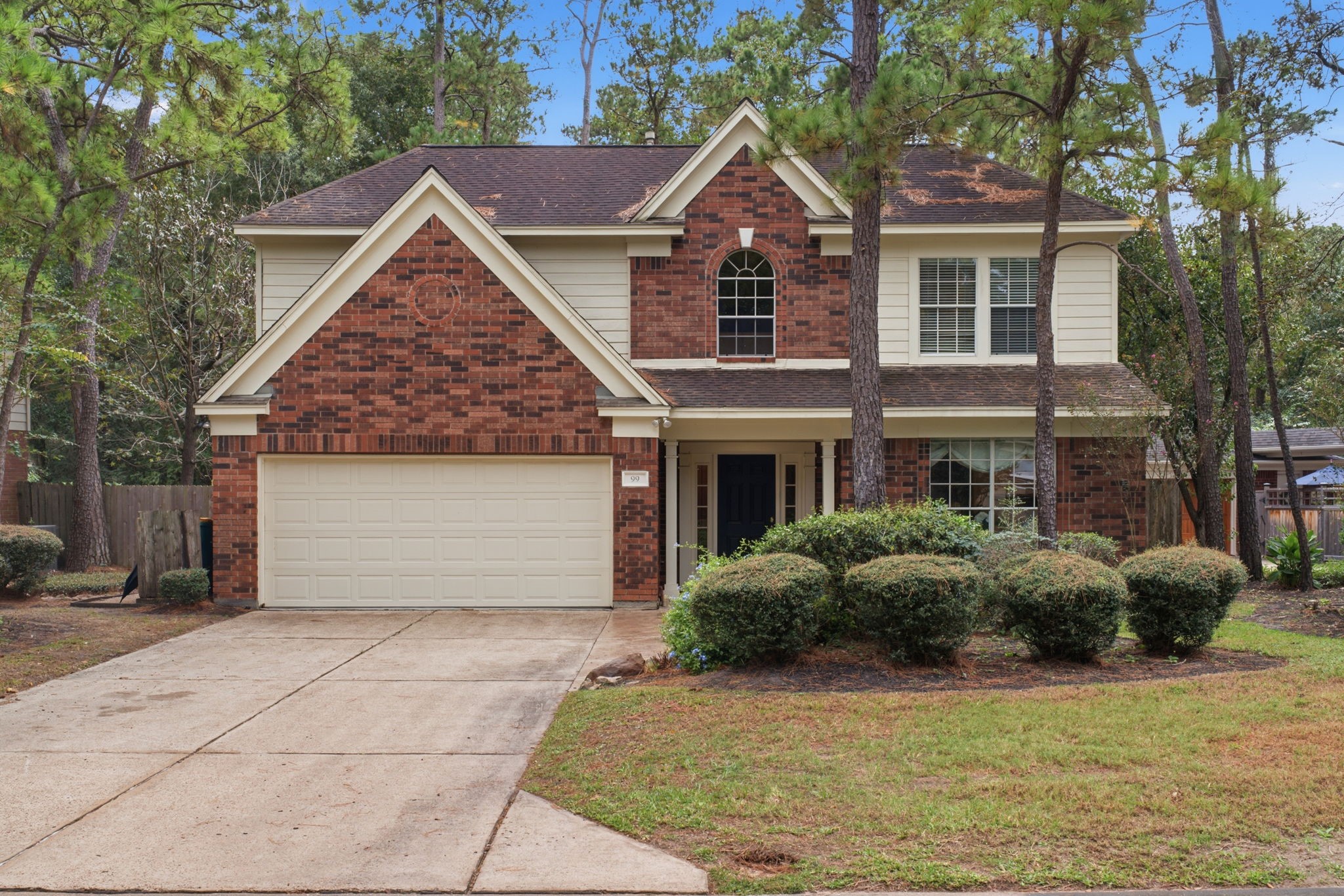 Charming two-story home with a classic brick facade, featuring a spacious two-car garage and beautifully landscaped front yard, nestled among mature trees for added privacy and curb appeal.