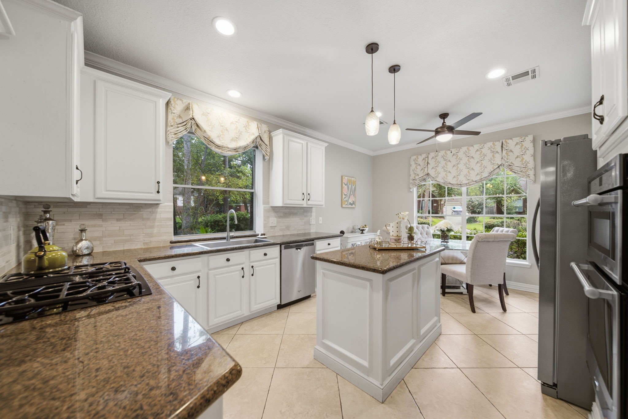 Bright and inviting kitchen featuring elegant white cabinetry, sleek countertops, and stainless steel appliances, complete with a cozy breakfast nook overlooking a lush garden.