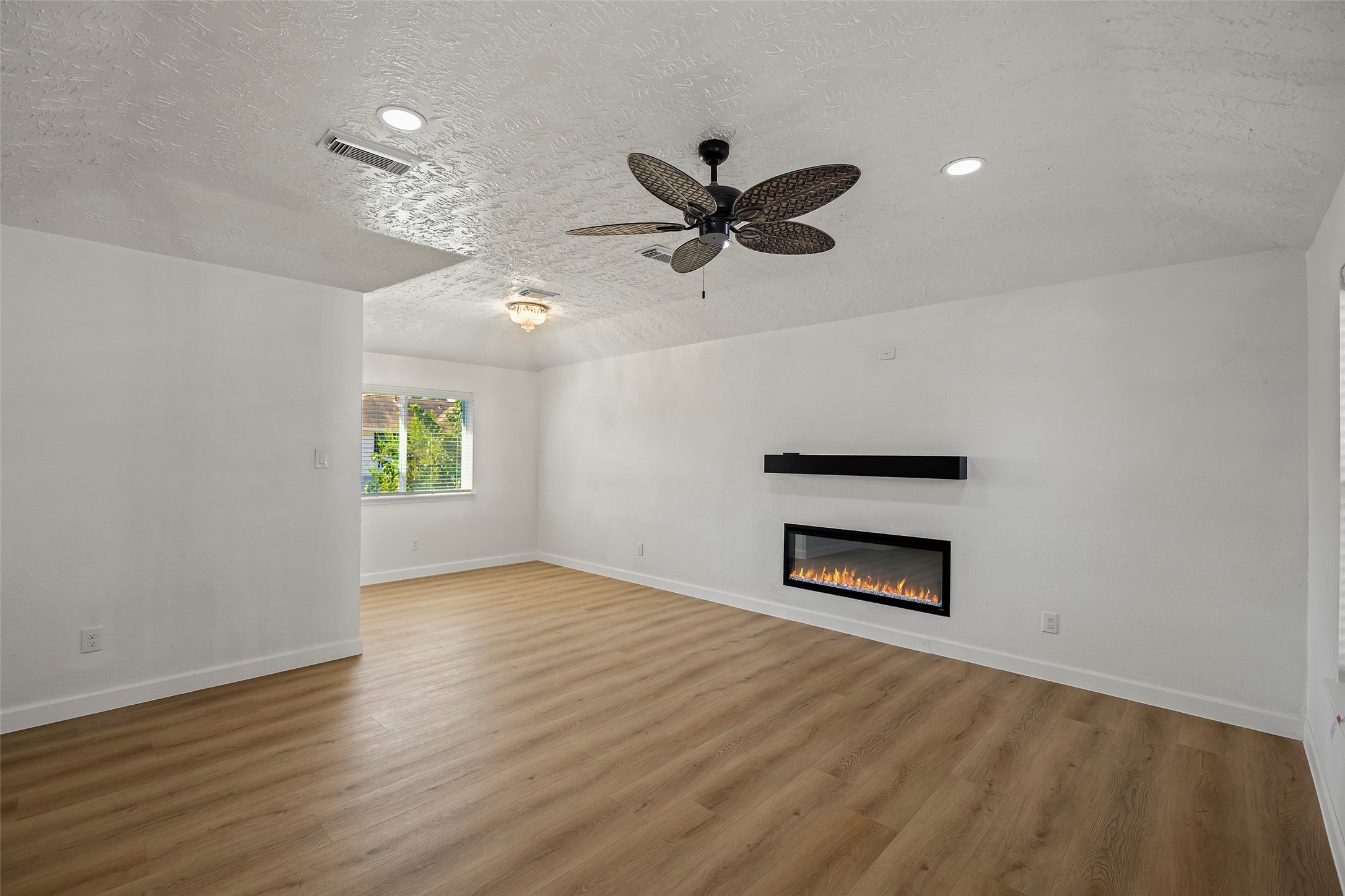 Spacious living area with vaulted ceilings, abundant natural light, and updated flooring.