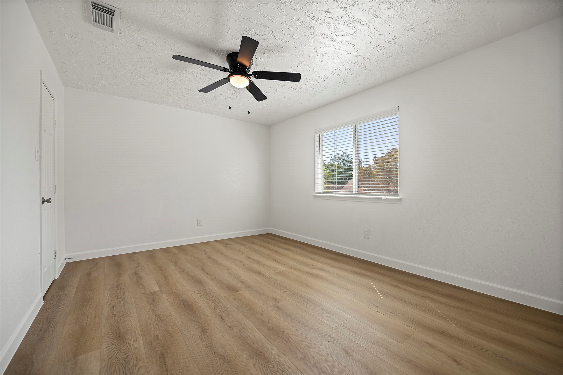 Spacious primary suite with new flooring and a new ceiling fan