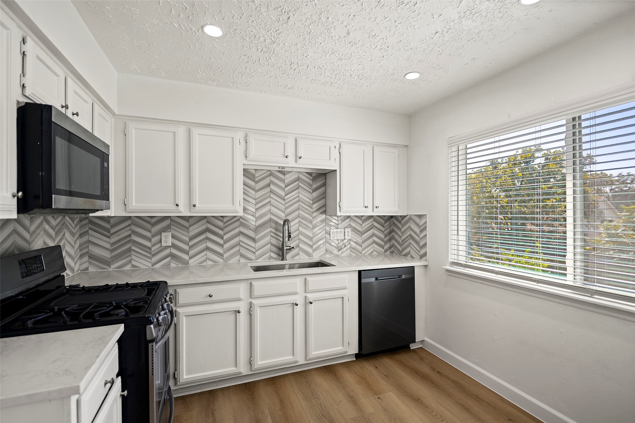 Updated kitchen featuring quartz countertops, white cabinetry, and stainless steel appliances.