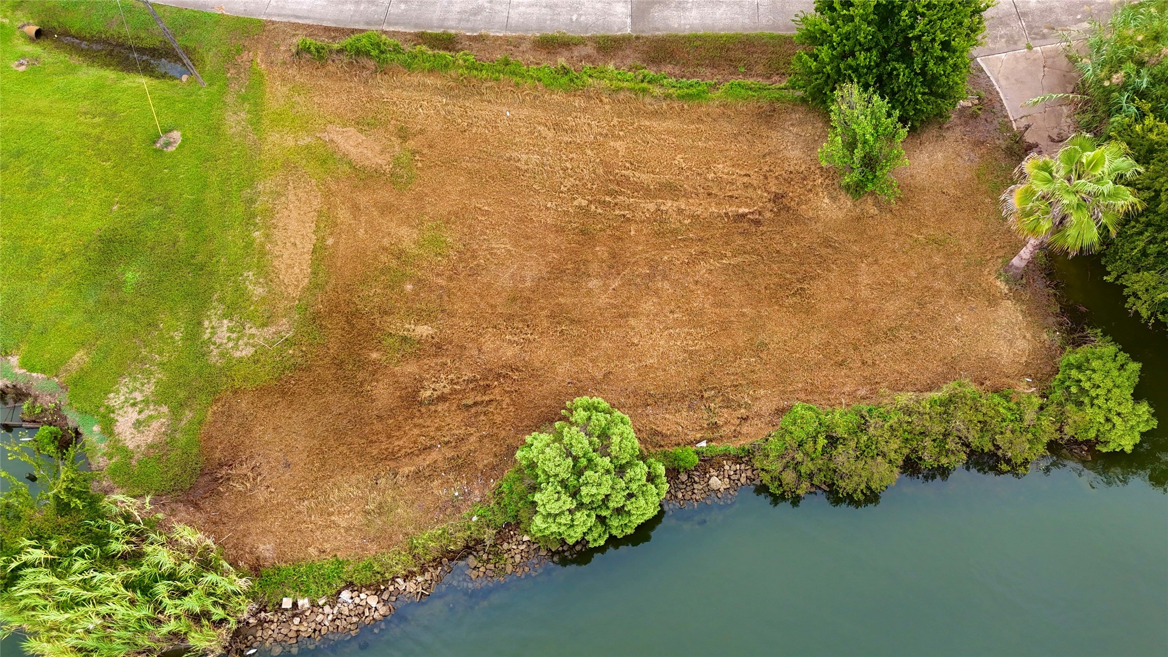 Aerial view of the waterfront lot showcasing the propertys layout, road frontage, & direct water frontage. Aerial view of the waterfront lot showcasing the propertys layout, road frontage, & direct water frontage.