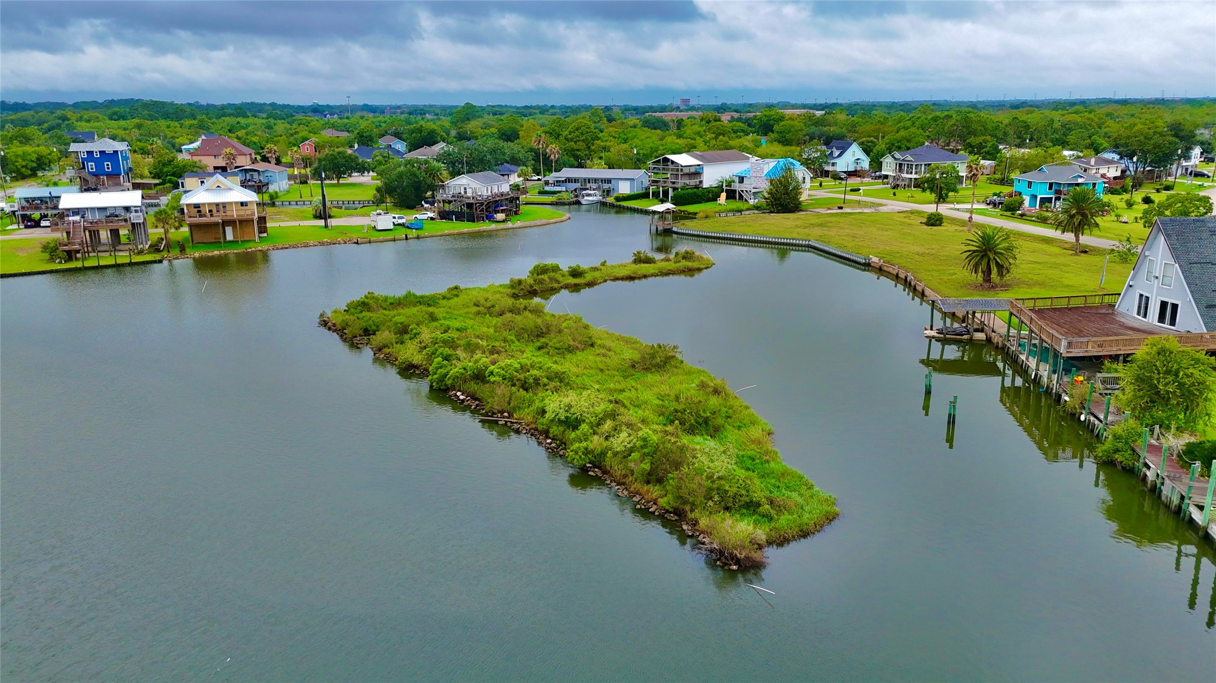Birds-eye view showcasing the local inlet, surrounding docks, and natural green island Birds-eye view showcasing the local inlet, surrounding docks, and natural green island