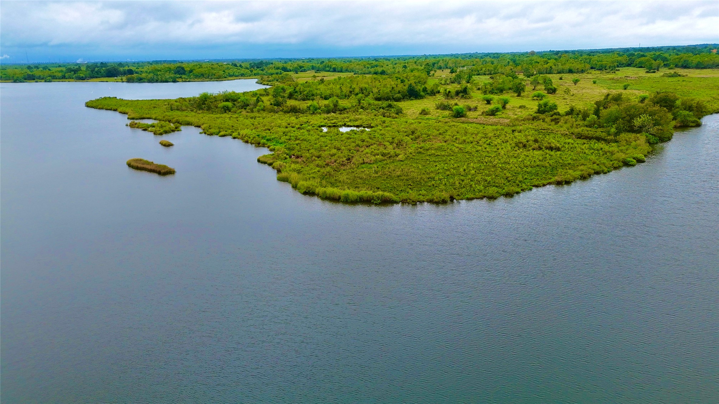 A closer aerial capture of the marshlands and green natural peninsula across the water from the property. A closer aerial capture of the marshlands and green natural peninsula across the water from the property.