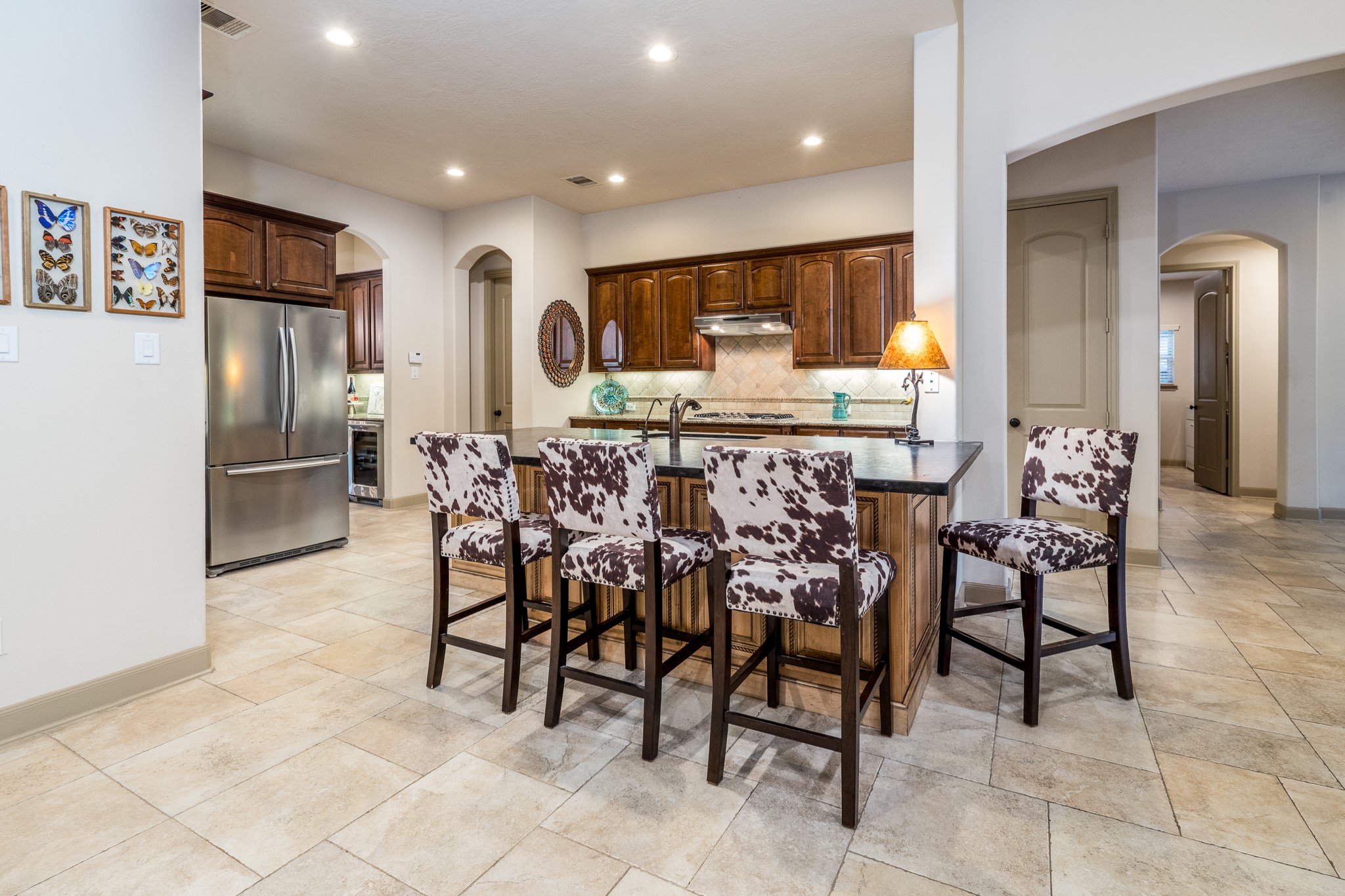 Where culinary inspiration meets timeless elegance! This beautifully remodeled kitchen is a true showpiece, featuring a spectacular statement island crowned with luxurious leather-finished granite that adds rich texture and sophisticated character. Abundant cabinetry, generous prep space, and an inviting breakfast bar create the perfect setting for everything from morning coffee to memorable gatherings. Seamlessly connected to the spacious family room, this exceptional kitchen is designed for those who love