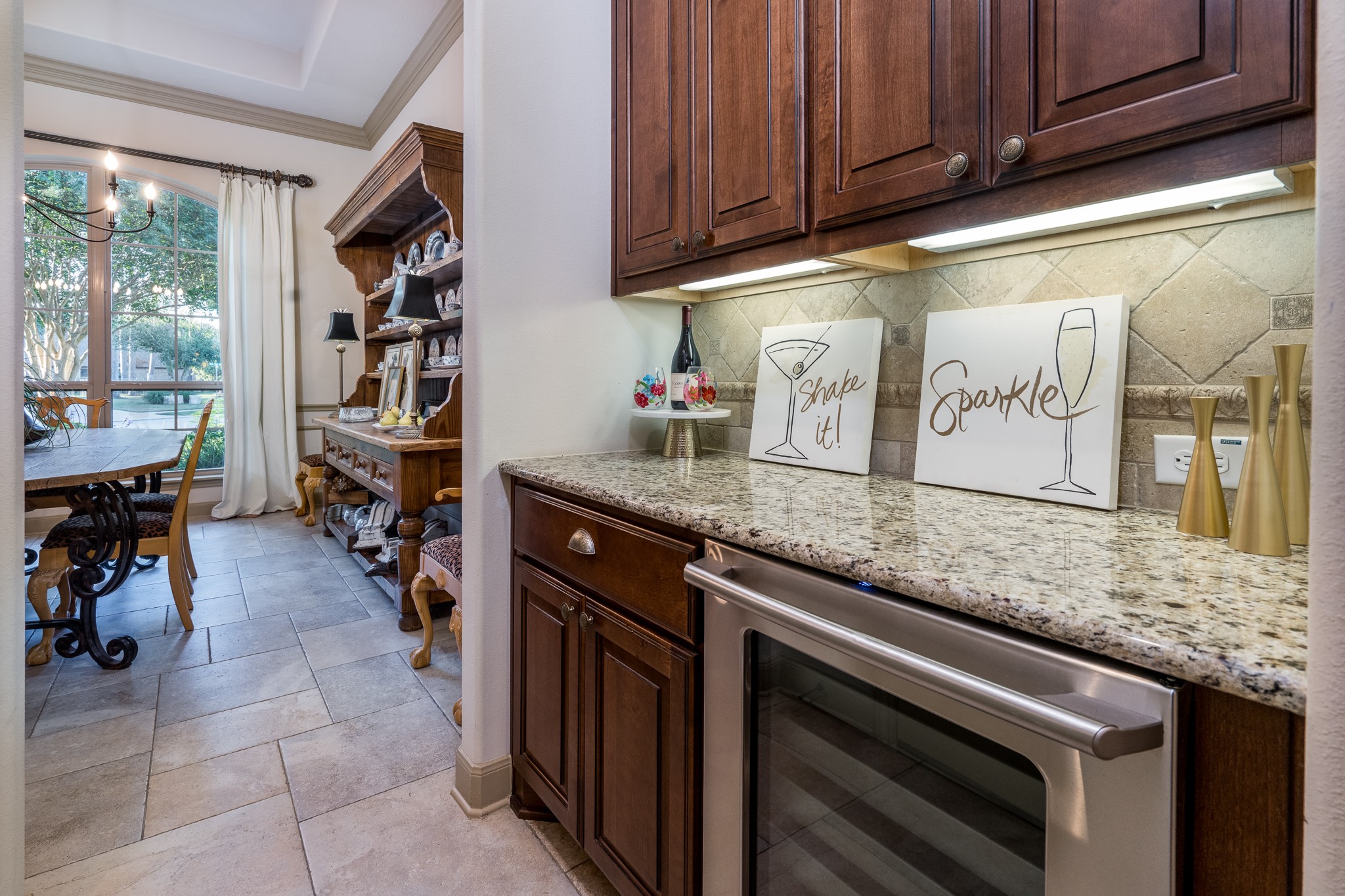 Entertaining has never been more effortless or elegant! This beautifully appointed butlers pantry and bar area features rich wood cabinetry, granite countertops, and a built-in wine refrigerator, creating the perfect space for preparing cocktails, serving guests, and keeping your favorite wines perfectly chilled. Conveniently positioned near the formal dining room, this sophisticated space adds both luxury and functionality to every gathering