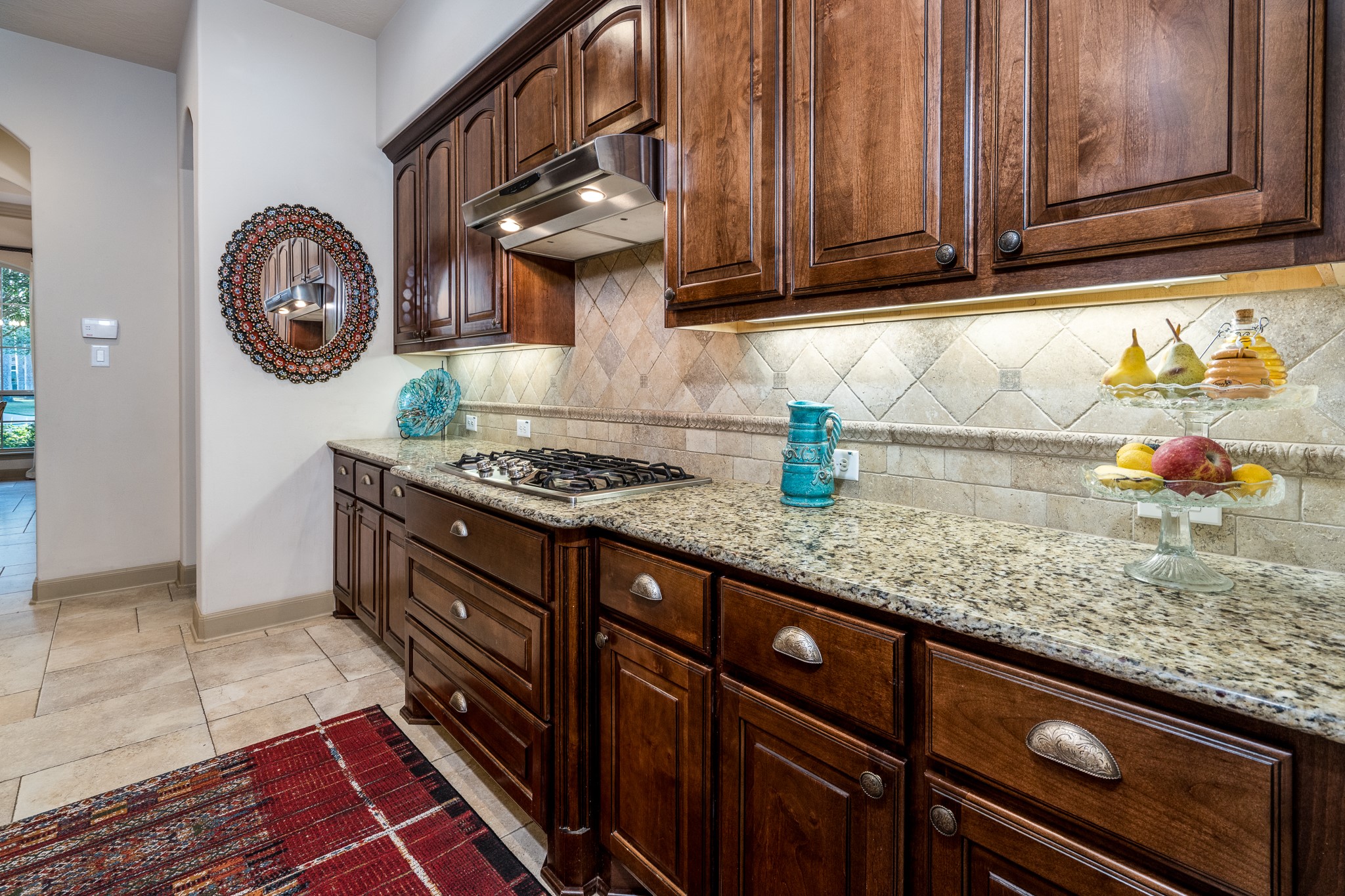 Timeless craftsmanship meets everyday luxury! Beautifully crafted rich wood cabinetry, gleaming granite countertops, and an elegant tile backsplash create a warm, sophisticated atmosphere. Generous counter space and abundant storage offer both beauty and functionality, making this thoughtfully designed kitchen a delightful space for preparing meals, entertaining guests, and enjoying life's everyday moments.