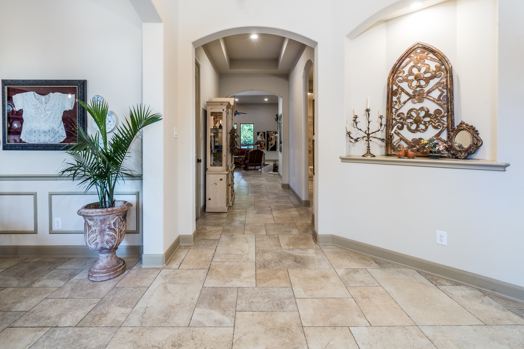ELEGANCE FLOWS THROUGH EVERY DETAIL! Beautiful arched doorways, timeless travertine flooring, and abundant natural light create a warm, inviting atmosphere. This graceful hallway offers a seamless transition between living spaces, showcasing the thoughtful architectural design and understated sophistication of this exceptional J. Patrick home!
