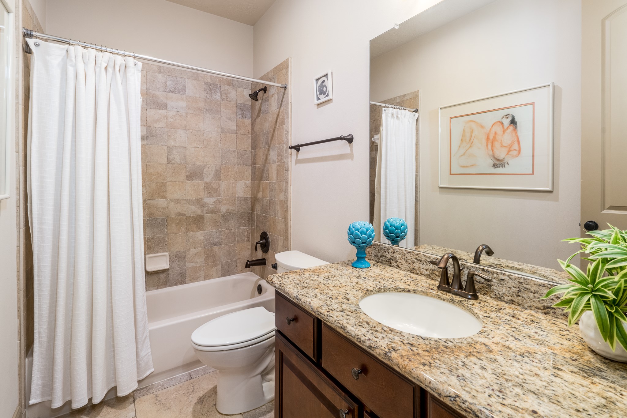 A WELCOMING TOUCH OF LUXURY FOR YOUR GUESTS! Beautifully appointed with elegant granite countertops, rich cabinetry, and timeless tile finishes, this inviting guest bathroom blends sophistication with everyday comfort. A spacious vanity and relaxing tub-and-shower combination create a thoughtfully designed retreat where guests can feel pampered and right at home!