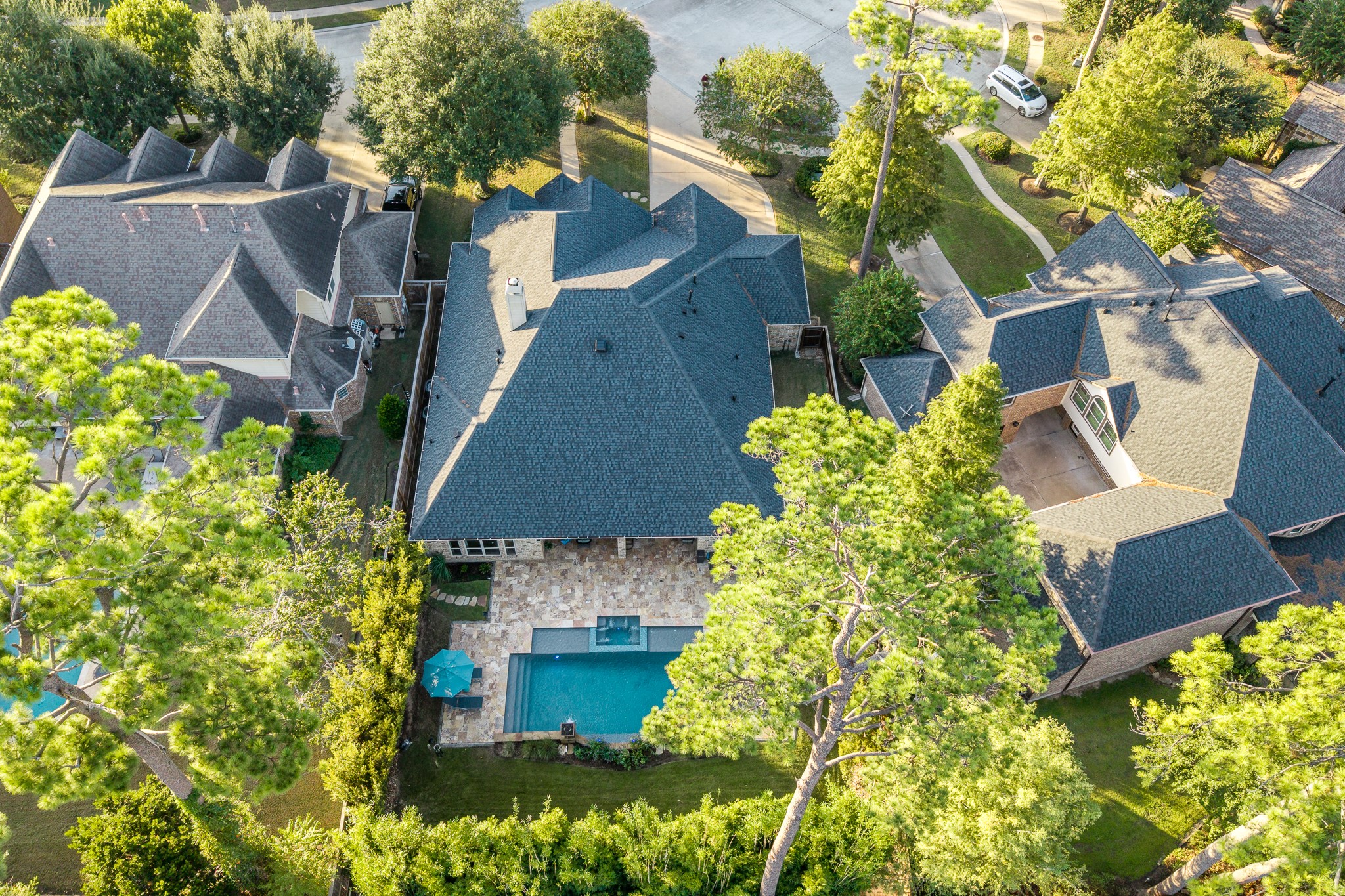 A Stunning Birds-Eye View of Luxury, Privacy, and Peace of Mind! This spectacular aerial perspective showcases the home's beautiful architectural design, new roof installed in 2024, and breathtaking backyard pool oasis. Surrounded by mature trees and lush landscaping, the property offers a wonderful sense of privacy while highlighting the expansive natural stone patio, sparkling pool, and inviting outdoor living spaces. A remarkable combination of timeless elegance and resort-inspired living!