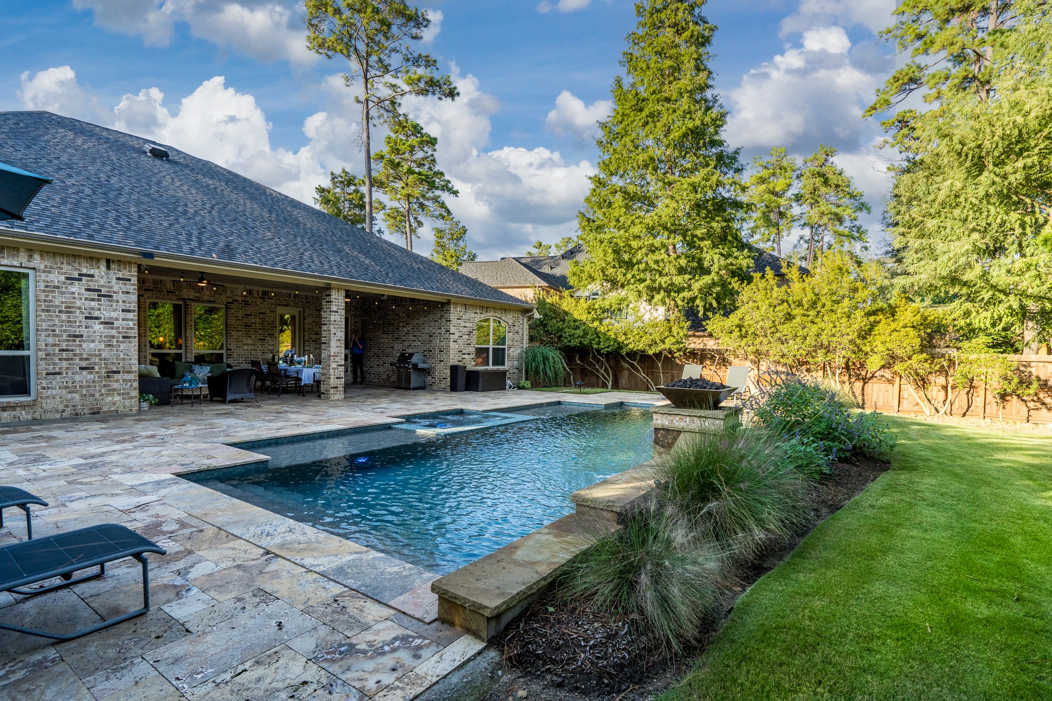 Where Everyday Living Feels Like a Luxury Vacation! This spectacular backyard oasis offers the perfect blend of relaxation, privacy, and outdoor entertaining. A sparkling resort-style pool, expansive natural stone decking, and a spacious covered patio create an inviting setting for gatherings or peaceful afternoons. Surrounded by lush landscaping and a beautifully manicured lawn, this exceptional outdoor retreat is designed for making memories that last a lifetime!