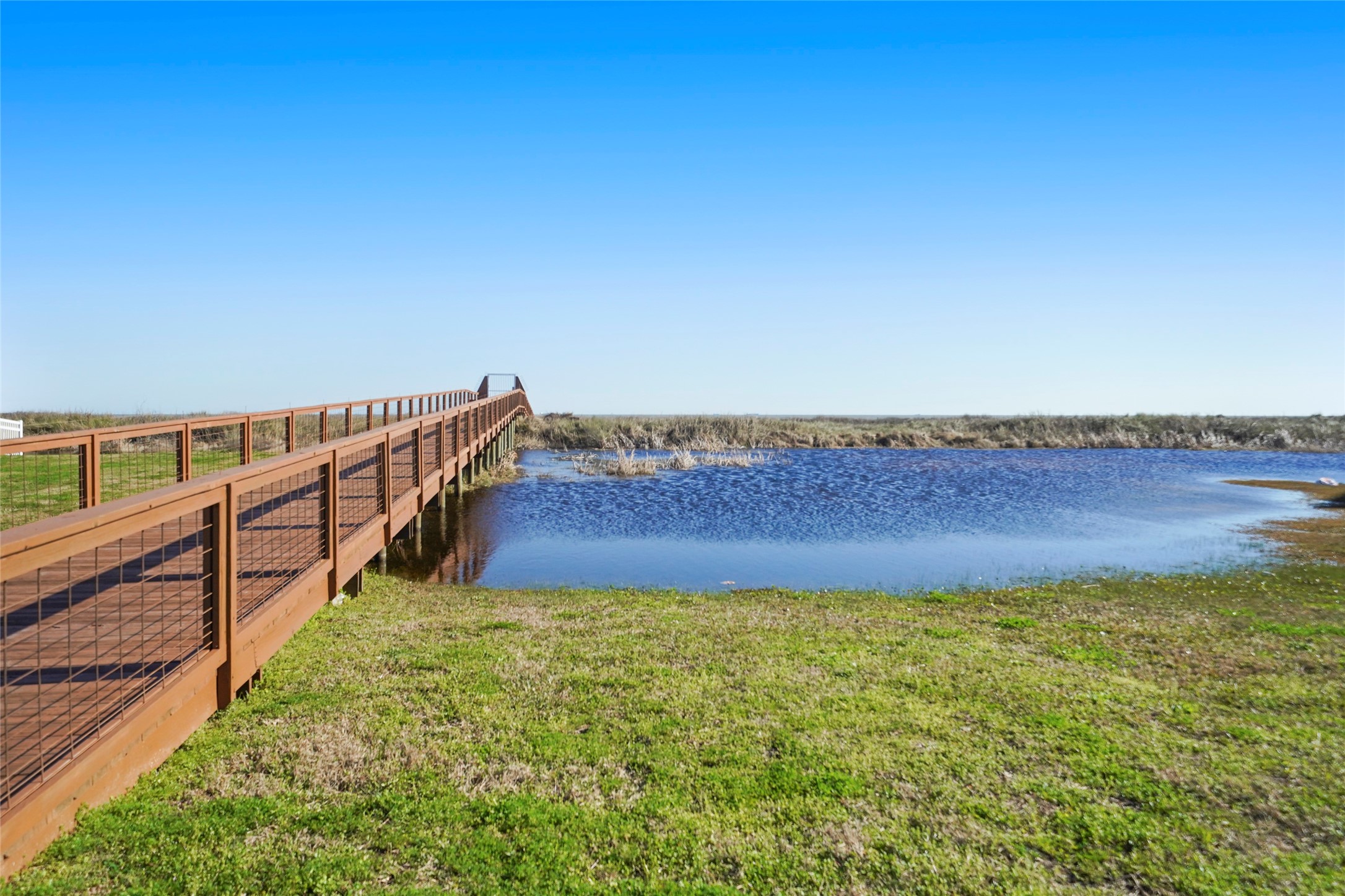 A closer view of the elevated community walkover highlights the direct connection residents enjoy to Galvestons natural coastal environment. The raised wooden boardwalk traverses the open landscape and provides dedicated pedestrian access toward the beach, creating an easy transition from the neighborhood to the shoreline.