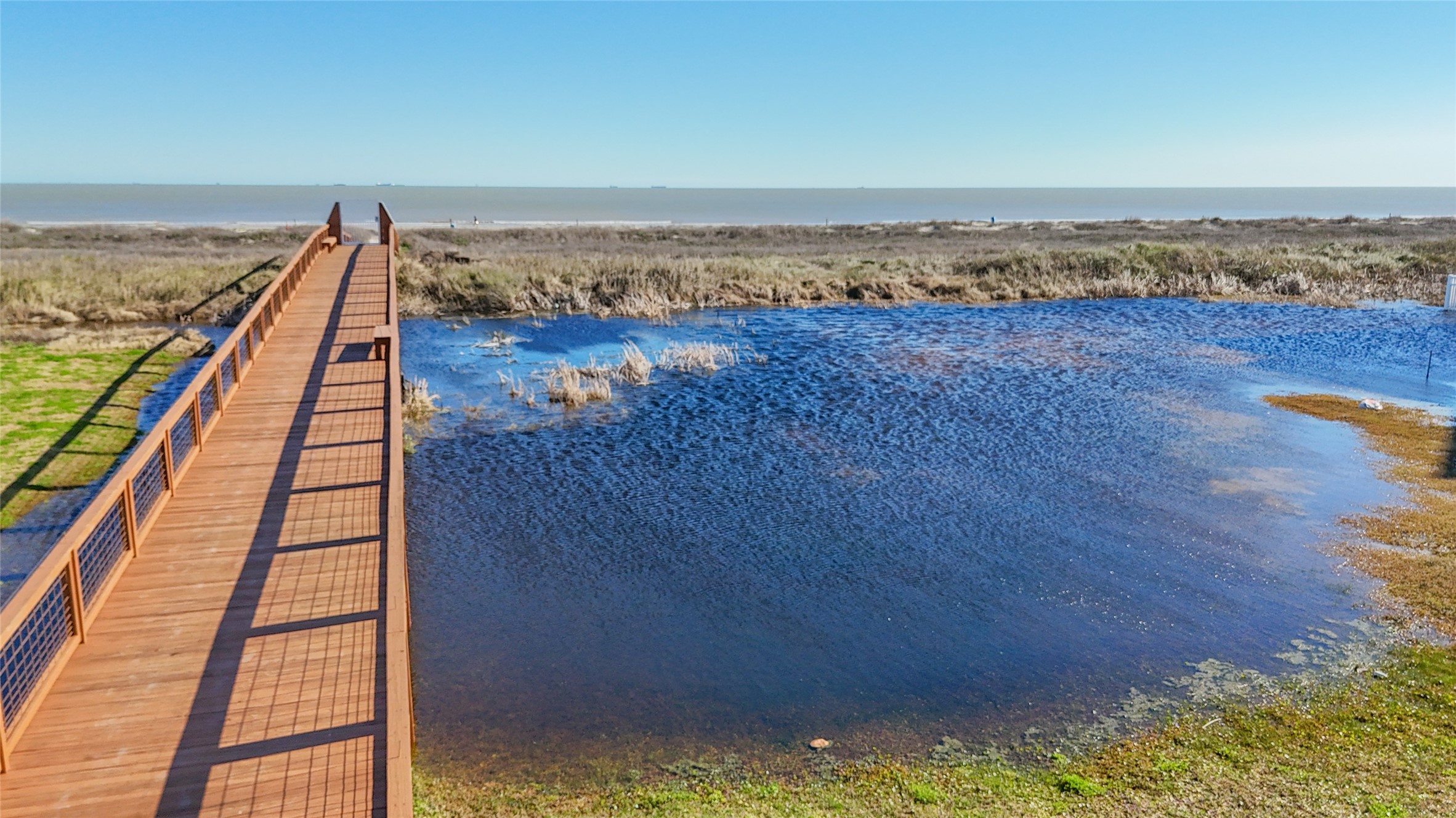 The communitys dedicated pedestrian walkover provides convenient access across the surrounding coastal landscape toward a quieter stretch of Galveston beach. This substantial elevated boardwalk creates a defined route for residents while preserving the natural terrain below. For 16 Grand Beach Boulevard, this amenity means sand, surf and Gulf sunrises are easily accessible without giving up the privacy and protected feel of a gated neighborhood.