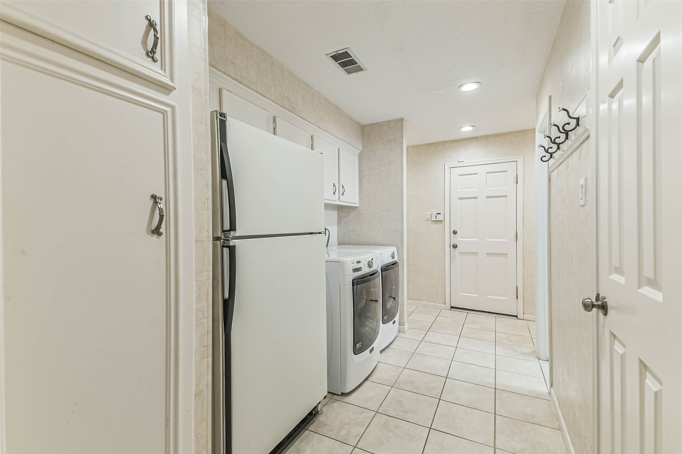 Utility room provides plenty of space for washer and dryer, extra fridge (included), and a half bathroom to the right.  Garage access straight ahead.