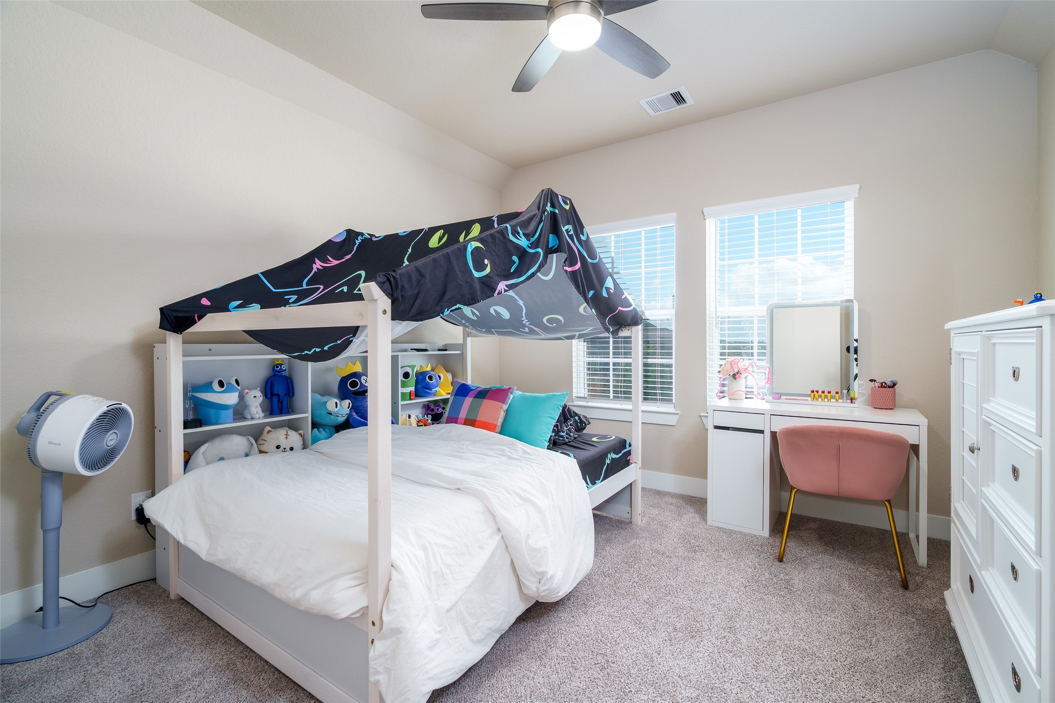 This inviting bedroom features plush carpet, windows for natural light, and a sleek modern ceiling fan for added comfort.