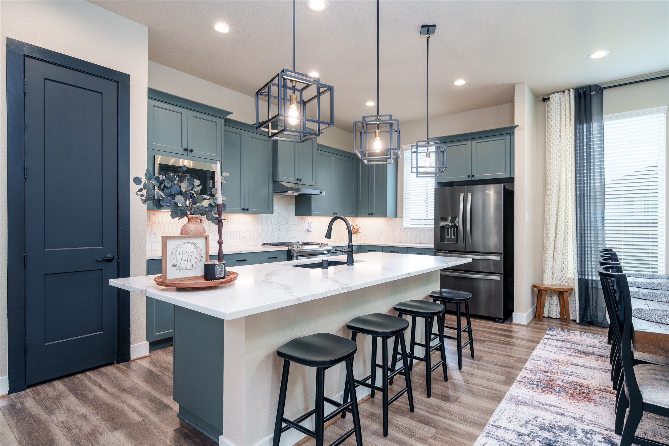 The kitchen is a chefs dream, featuring custom painted cabinets, sleek, upgraded granite countertops, a spacious kitchen island, and modern pendant lighting that beautifully illuminates the space.