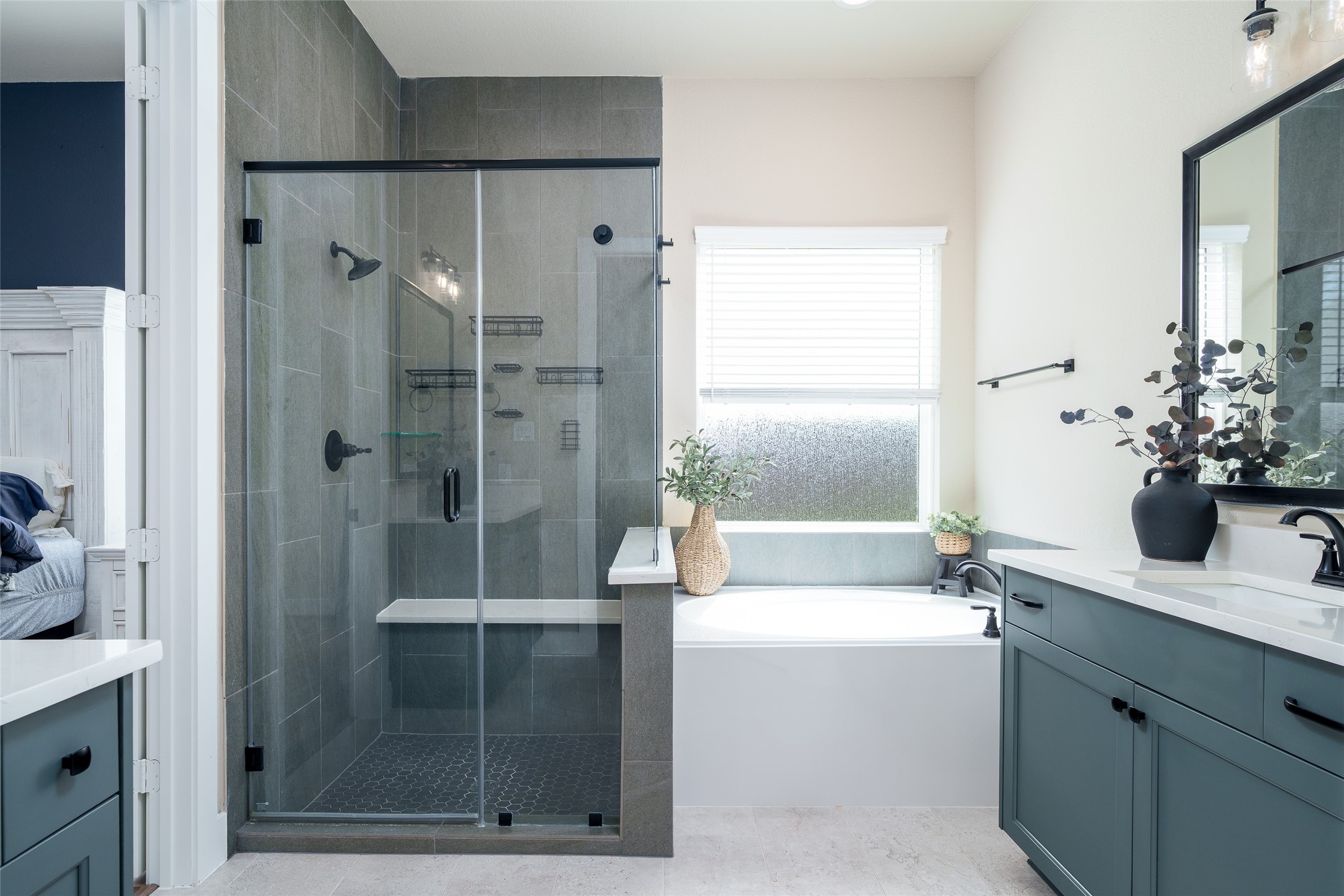 The primary bathroom is a luxurious haven, featuring a tiled walk-in shower, a spacious bathtub for ultimate relaxation, and double sink vanities with sleek custom paint adorned with modern black hardware for a stylish touch.