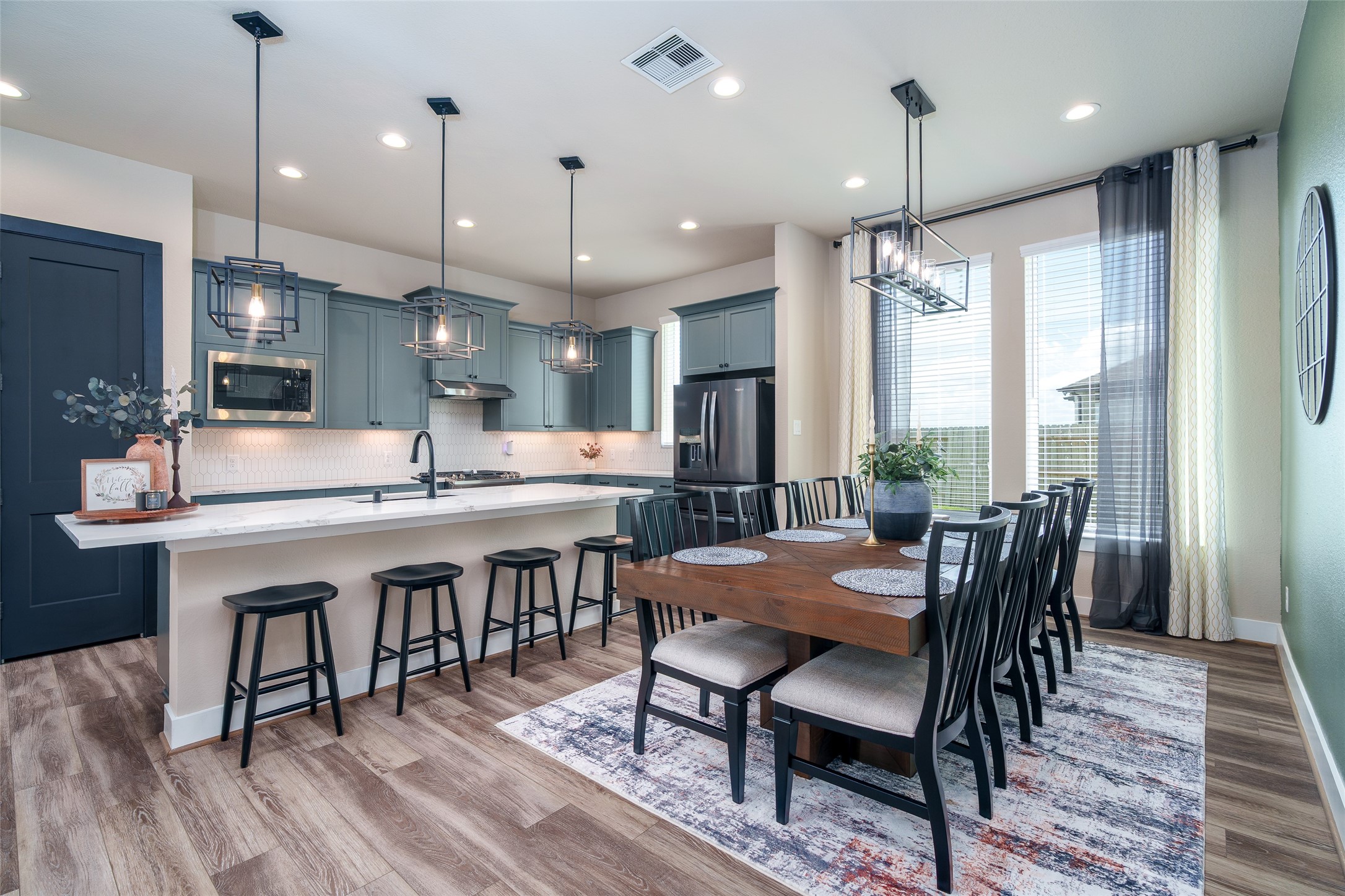 The bright and inviting dining area, located next to the kitchen, features multiple windows for natural light, stylish chandelier, and sleek recessed lighting that's perfect for enjoying your morning coffee!