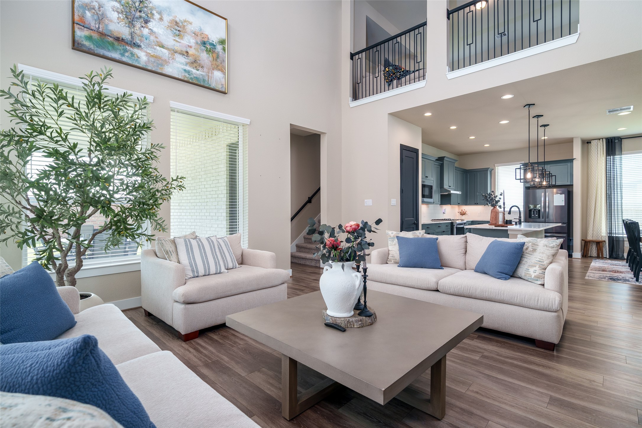 The spacious living room boasts soaring high ceilings, beautiful LVP flooring, and large windows with privacy blinds that fill the space with natural light while maintaining comfort and seclusion.