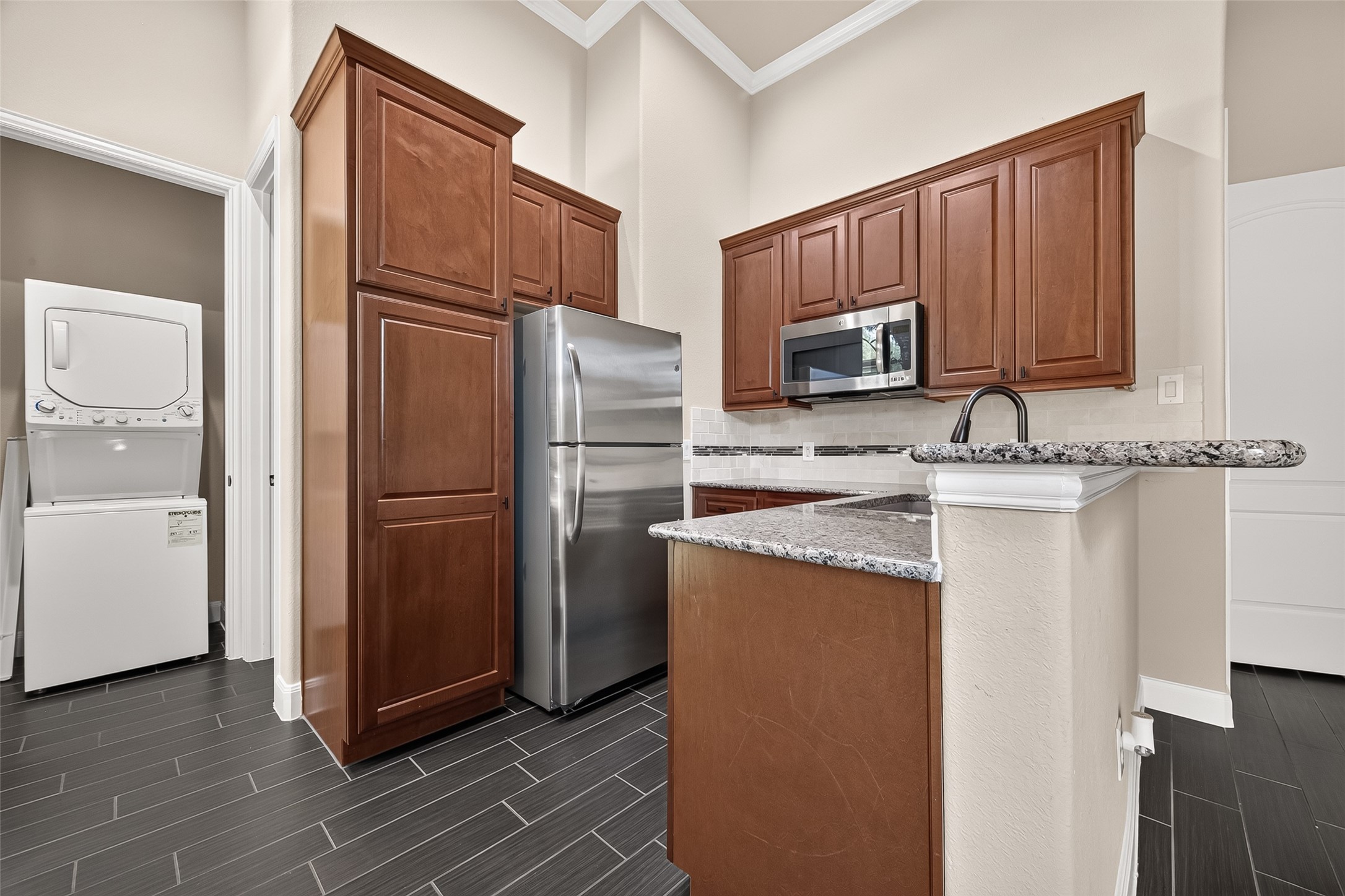 Kitchenette: kitchenette featuring granite countertops, stainless steel appliances, refrigerator, electric cooktop, eat-up bar, beautiful cabinetry, a private bedroom with en-suite bath, and its own laundry area!