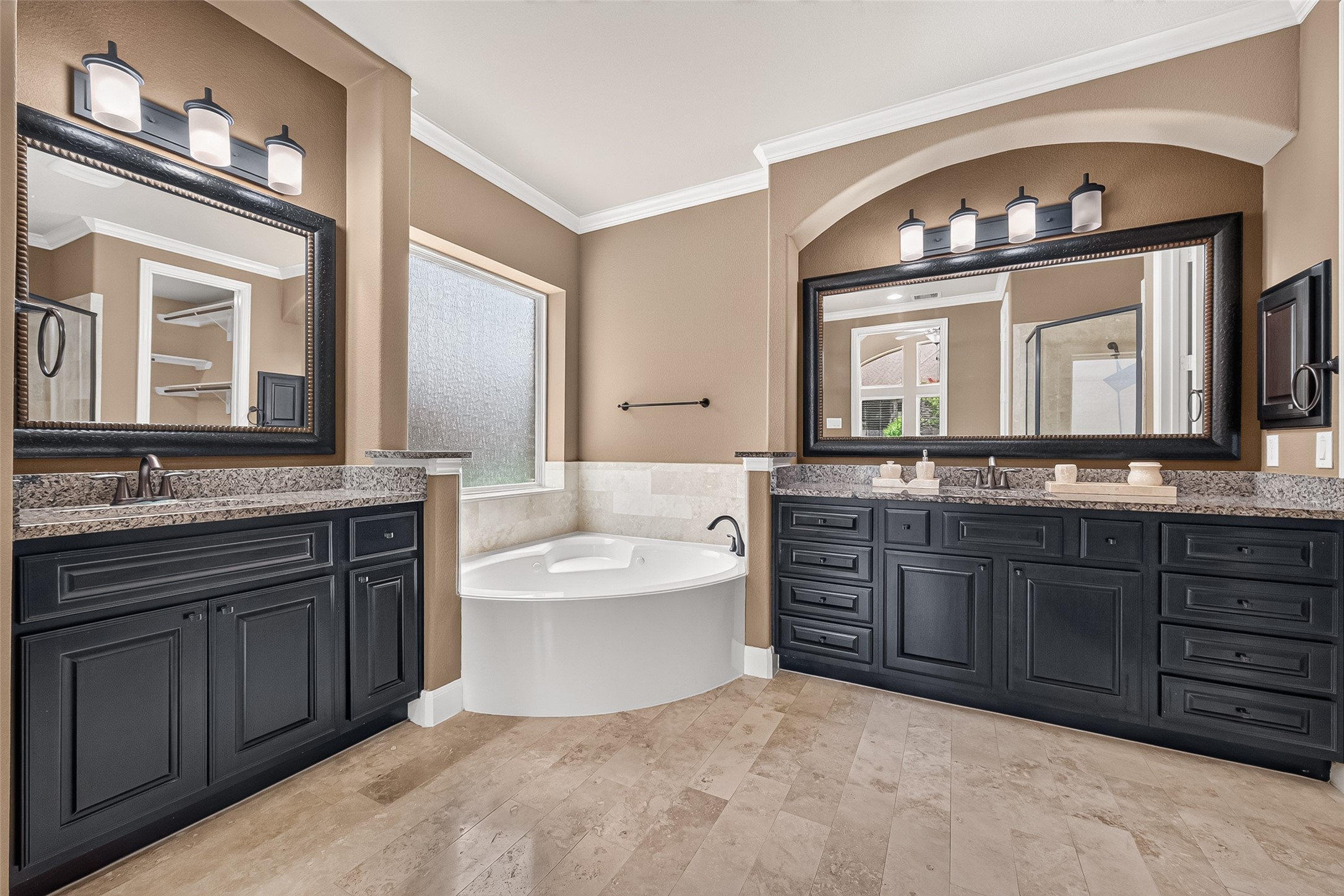 Primary Ensuite: Double doors lead into the spa-inspired primary bath featuring a corner soaking tub, separate shower, dual vanities, elegant cabinetry, and oversized vanity mirrors.