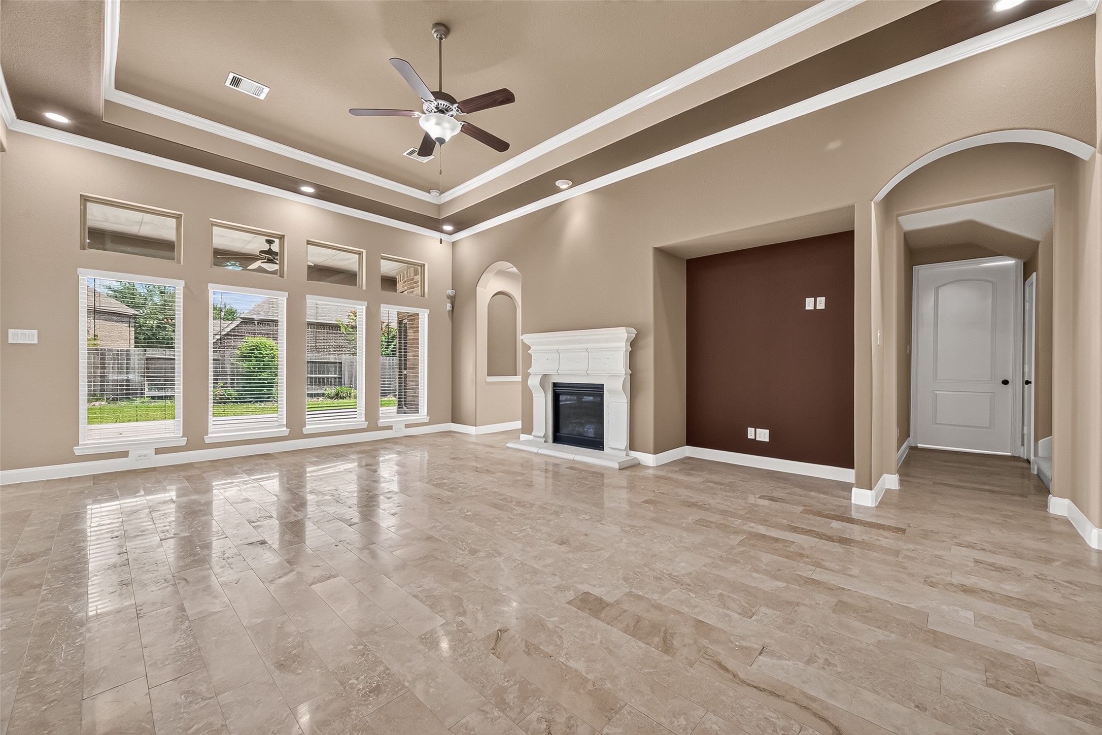 Family Room: The spacious family room boasts a cast-stone fireplace, tray ceilings, and a dramatic wall of windows that fills the home with natural light and views of the backyard patio. Family Room: The spacious family room boasts a cast-stone fireplace, tray ceilings, and a dramatic wall of windows that fills the home with natural light and views of the backyard patio.