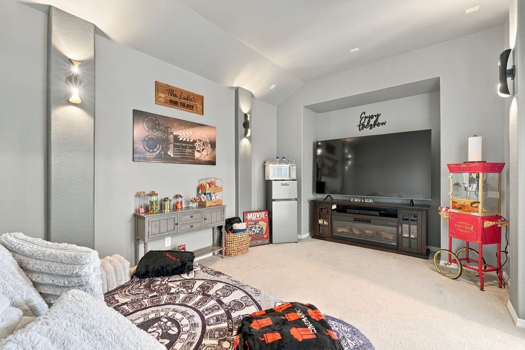 Cozy home theater featuring surround sound, a large screen, ambient lighting, and a popcorn machine, perfect for movie nights.