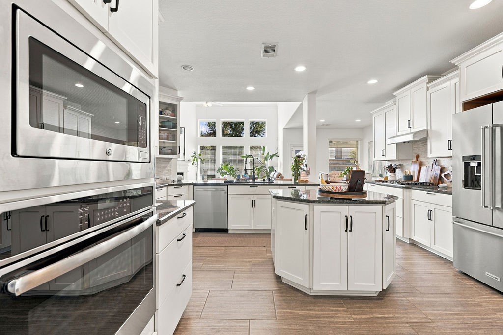 Spacious kitchen with sleek stainless steel appliances, elegant white cabinetry, and a central island perfect for meal prep and entertaining.