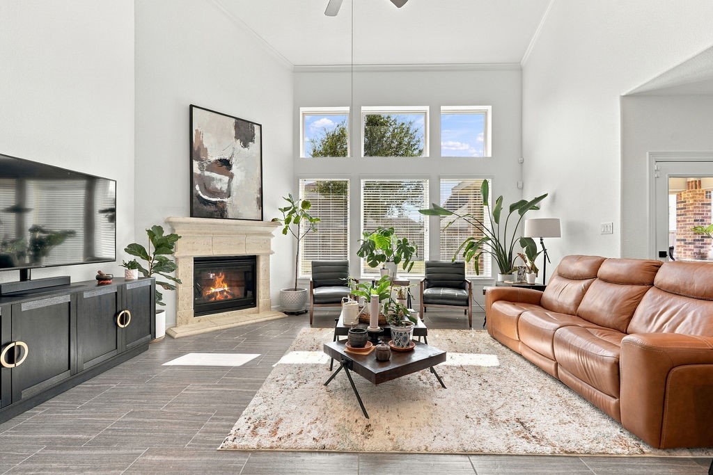 Spacious living room with high ceilings, large windows, and abundant natural light. A cozy fireplace anchors the room, complemented by modern furnishings and elegant decor.