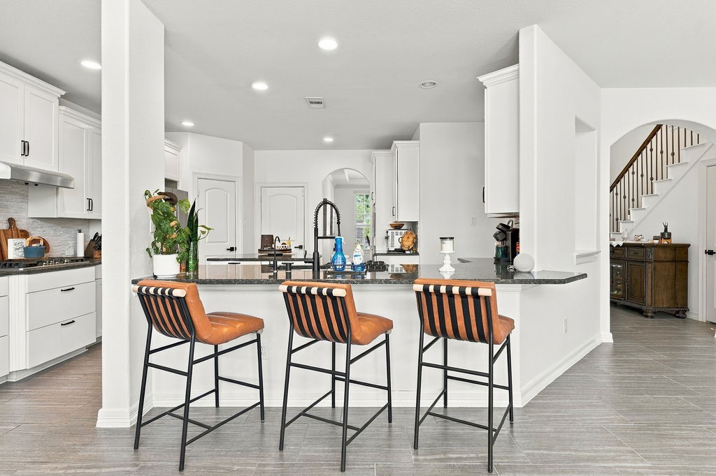 Modern kitchen featuring sleek white cabinetry, a large island with stylish bar seating, and elegant granite countertops, perfect for entertaining and culinary adventures.