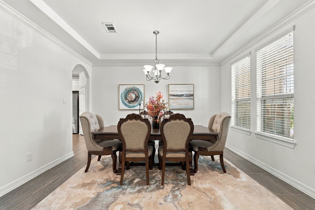 Elegant dining room featuring a sophisticated chandelier, large enough for 8-10 chair dining set and has abundant natural light from large windows.