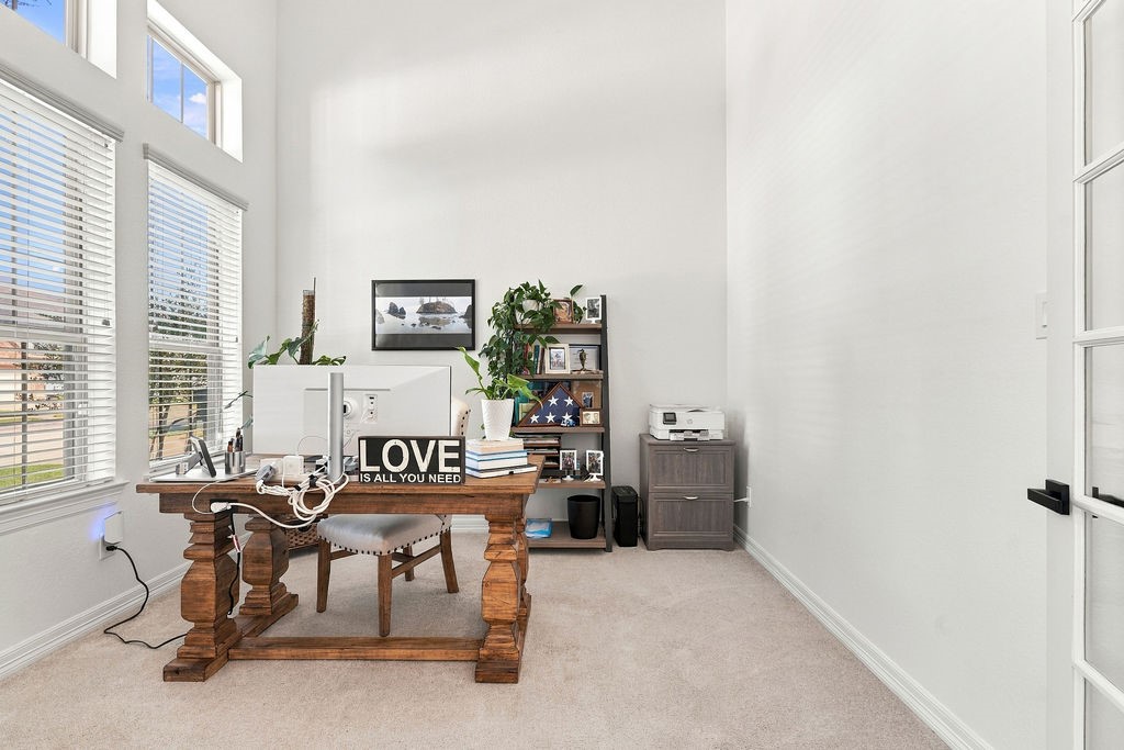 Bright and inviting office space with high ceilings, large windows for natural light, and elegant wood furniture creating a productive work environment.
