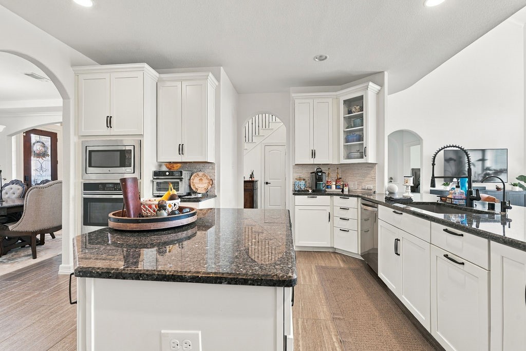 Spacious kitchen with sleek granite countertops, modern appliances, and ample white cabinetry, offering both functionality and style.