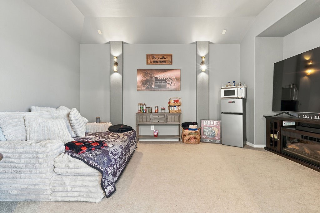 Cozy entertainment room featuring plush seating, a large flat-screen TV, and a mini refreshment area with a microwave and fridge, perfect for movie nights.