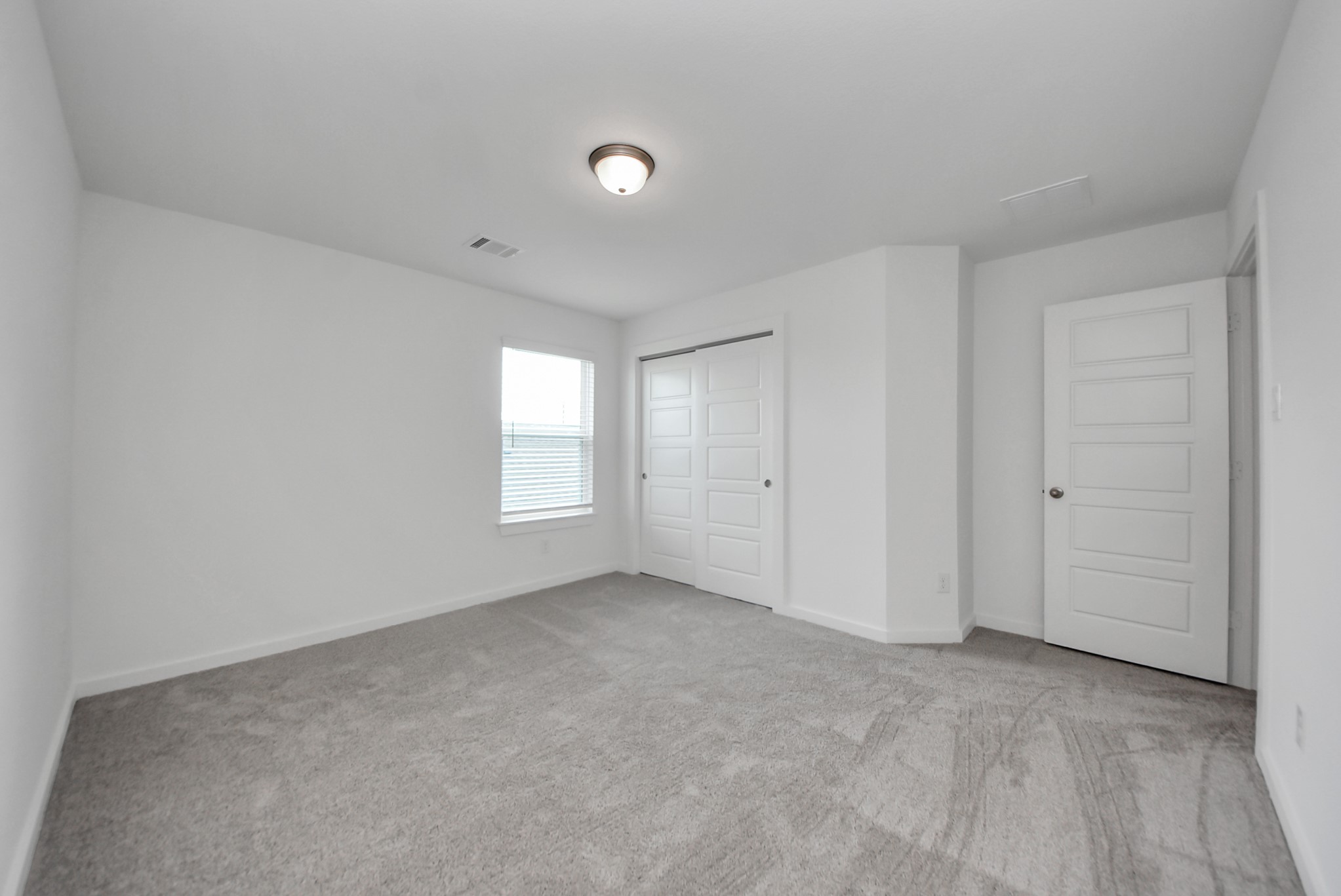 Secondary bedroom features plush carpeting, large windows that let in plenty of natural light, bright paint, and spacious closets.