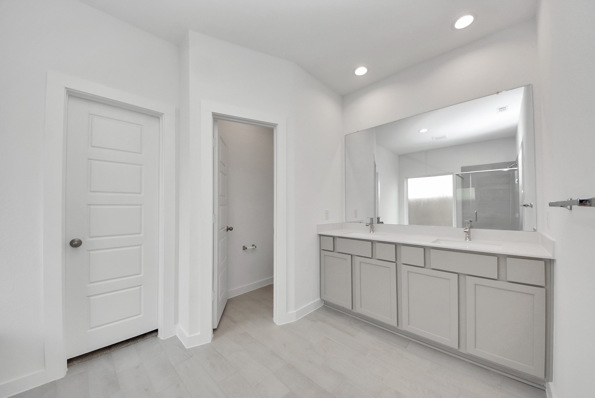 Elevate your daily routine at the elegant vanity, now equipped with double sinks, light countertops, modern hardware, and beautiful recessed lights.