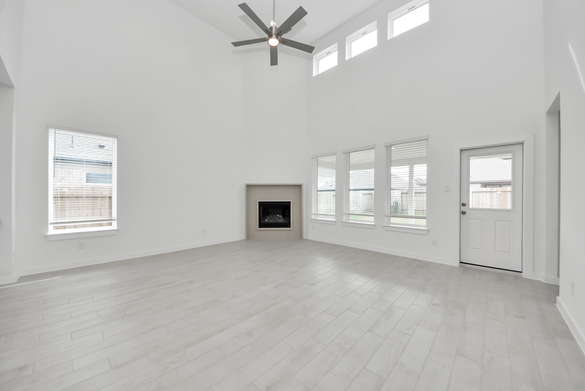 Relax and unwind in this inviting family room, illuminated by abundant natural light streaming in through tall windows, complemented by high ceilings and stunning flooring. Stay comfortable year-round with the gentle breeze from the ceiling fan, creating the perfect atmosphere for family gatherings.
