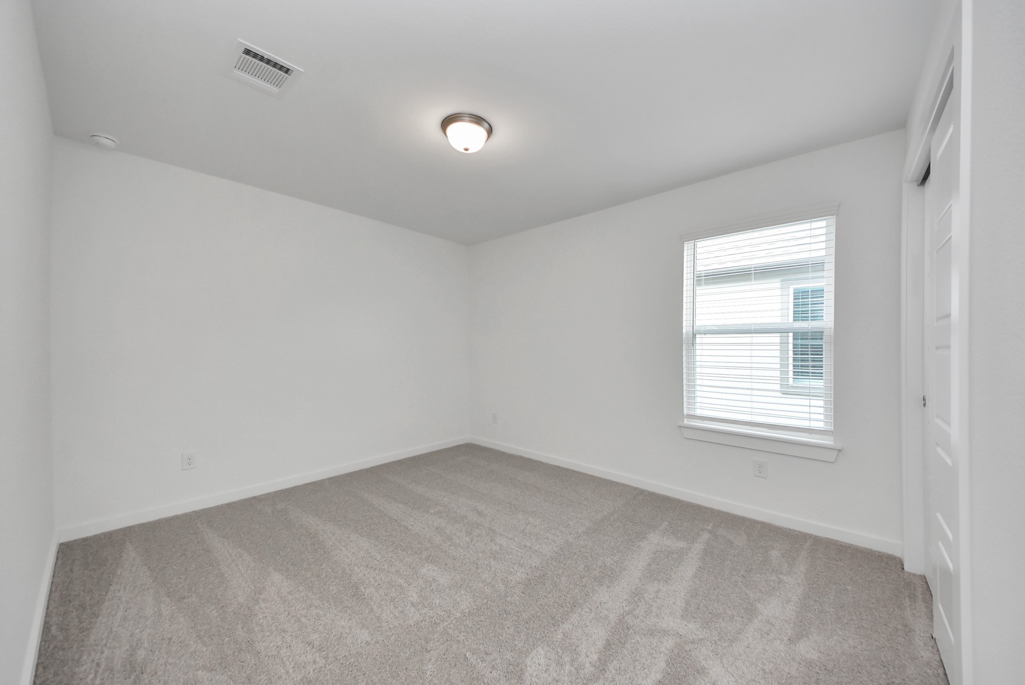 Secondary bedroom features plush carpeting, large windows that let in plenty of natural light, bright paint, and spacious closets.