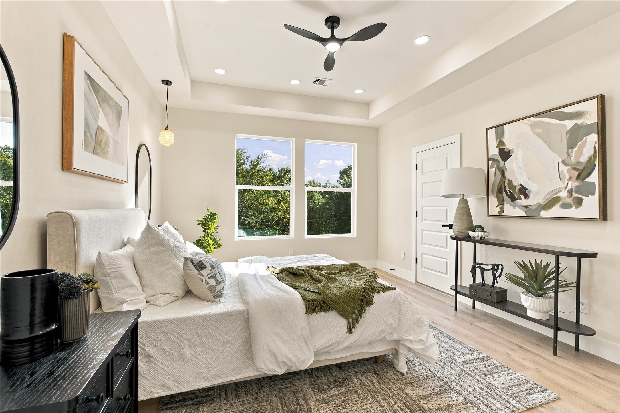 Wake up rejuvenated  cozy primary bedroom layout framed by green treetop views and soft sunlight.