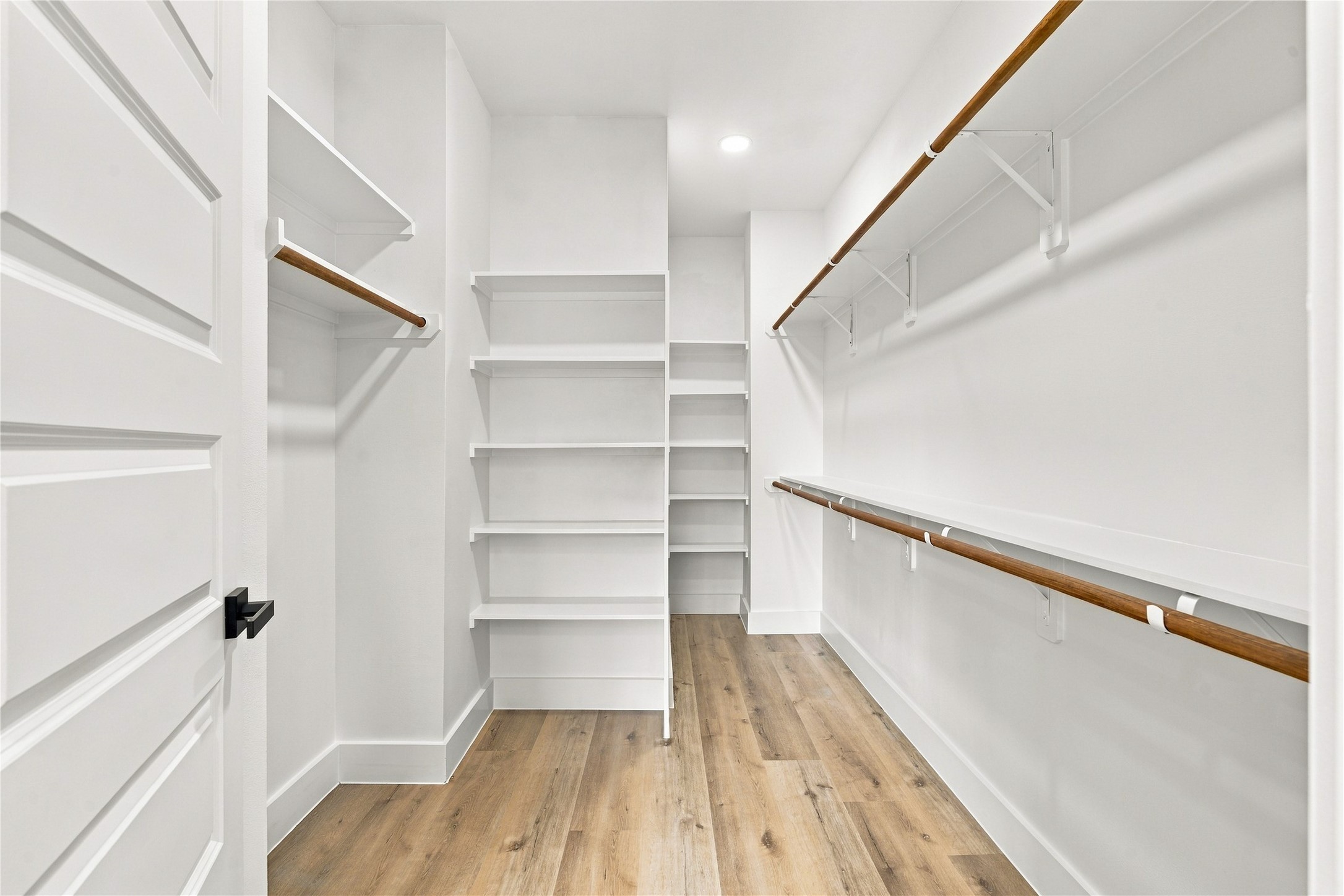 Custom walk-in closet  extensive multi-level hanging rods and shoe shelving tailored for maximum organization.