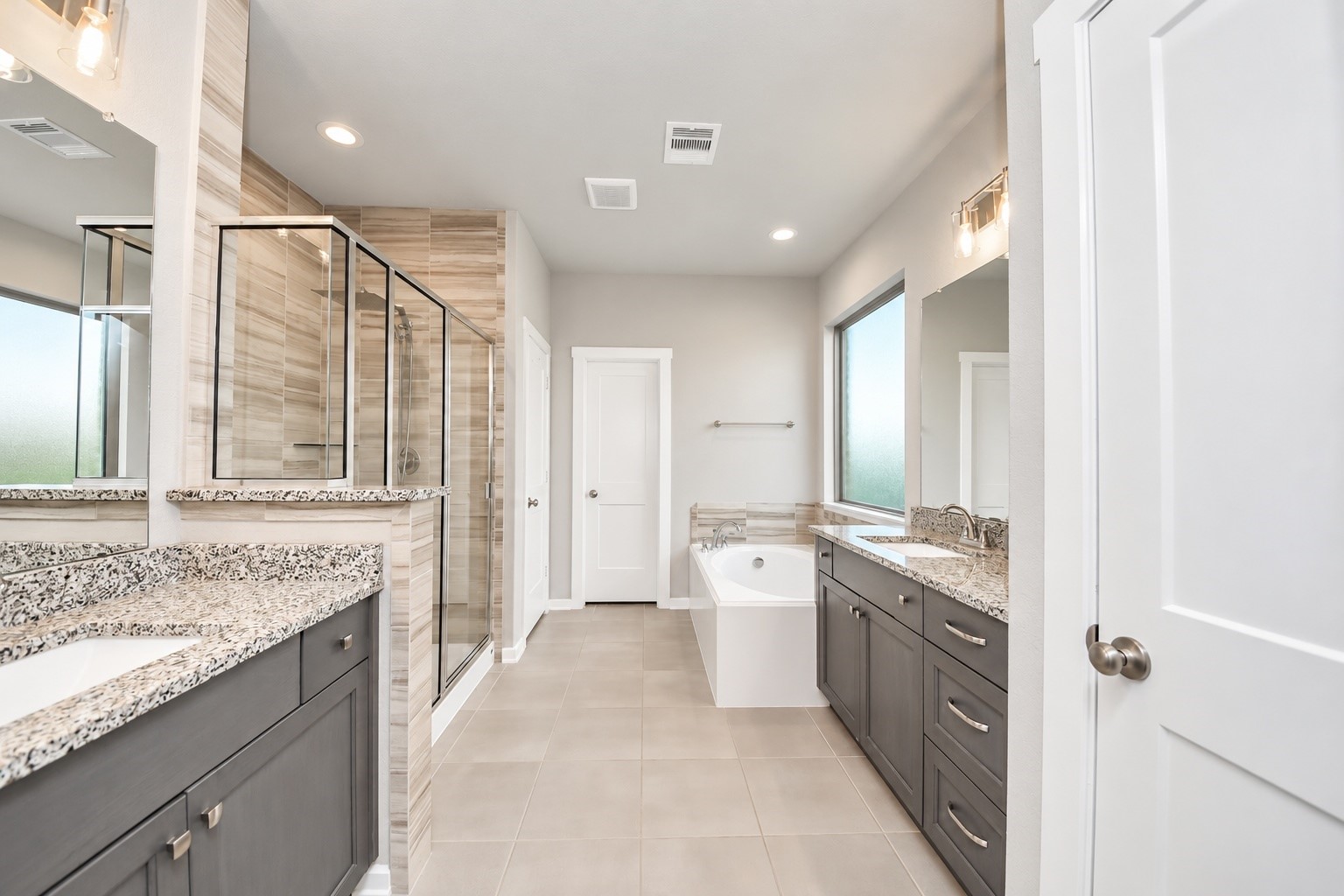 Luxurious primary bathroom featuring an oversized glass-enclosed shower, dual vanities, generous countertop space, and stylish finishes.