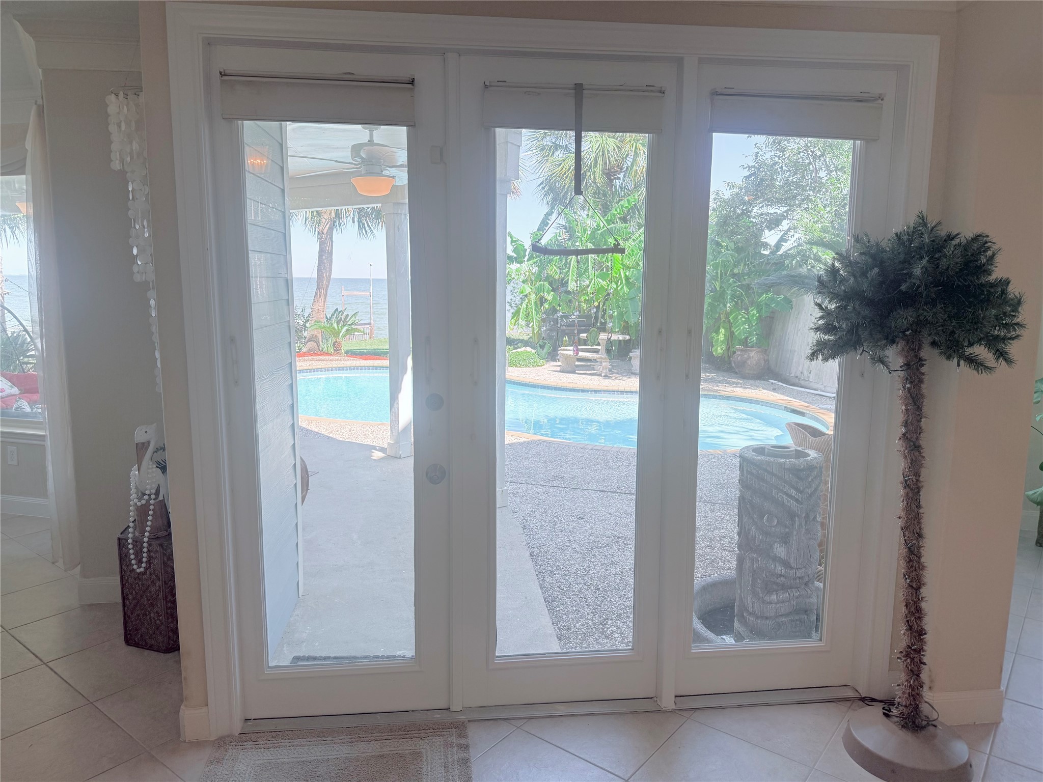 Glass doors overlooking the pool, garden and water view.