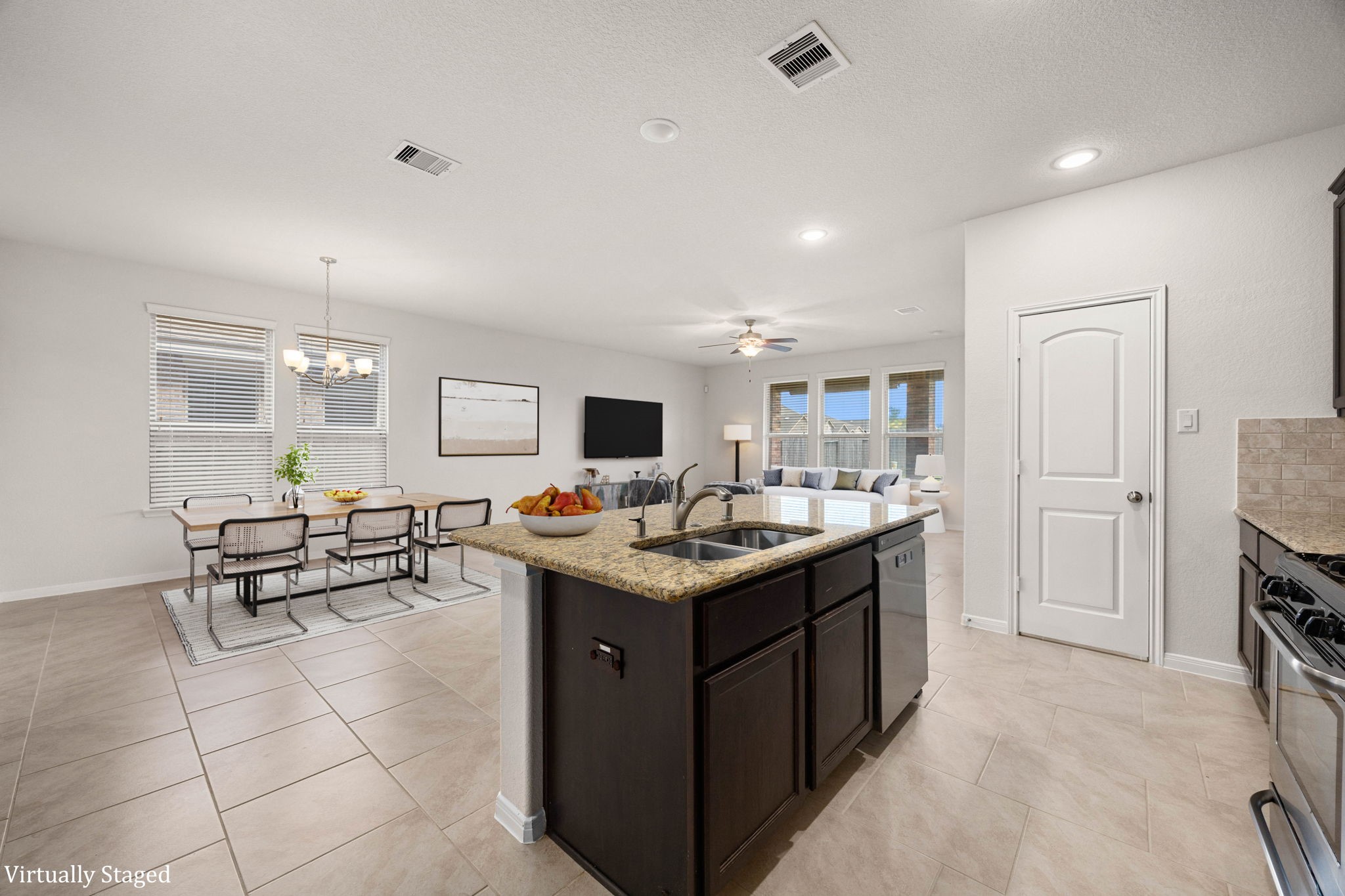 Bright and airy open-concept kitchen and dining area featuring a central granite-topped island with an integrated double sink and matching rich espresso cabinetry.