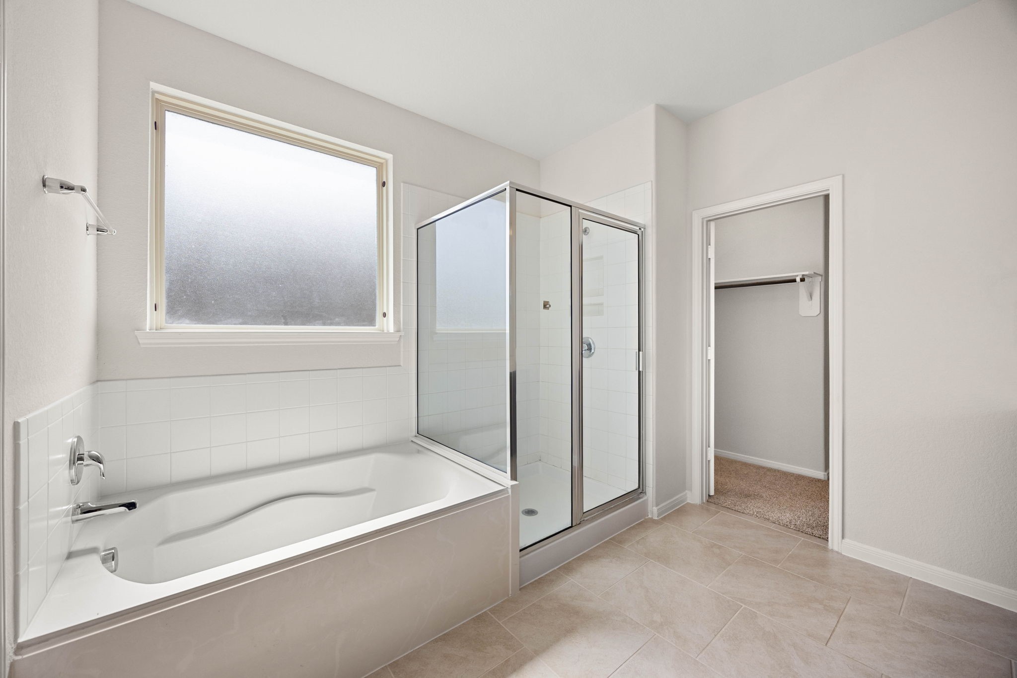 Spa-like primary bathroom oasis boasting a deep soaking tub, a separate glass-enclosed shower, and bright, private natural light.