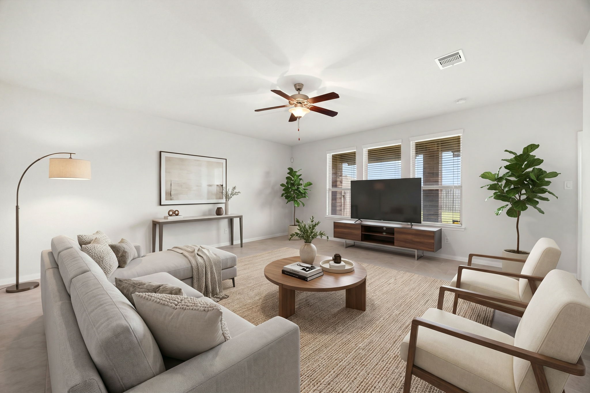 Spacious and sun-drenched living area featuring expansive neutral flooring, large triple-pane windows, and a central modern ceiling fan with an integrated light fixture.